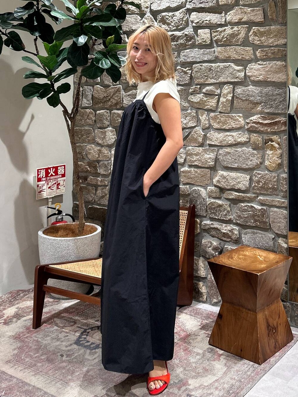 レッド系のサンダル、ブラック系のジャンパースカートを着用したレディースの春コーディネートの2枚目の写真