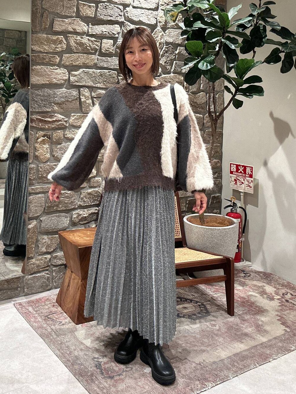 ブラウン系のニット/セーター、ブラック系のブーツ、シルバー系のスカートを着用したレディースの冬コーディネートの2枚目の写真