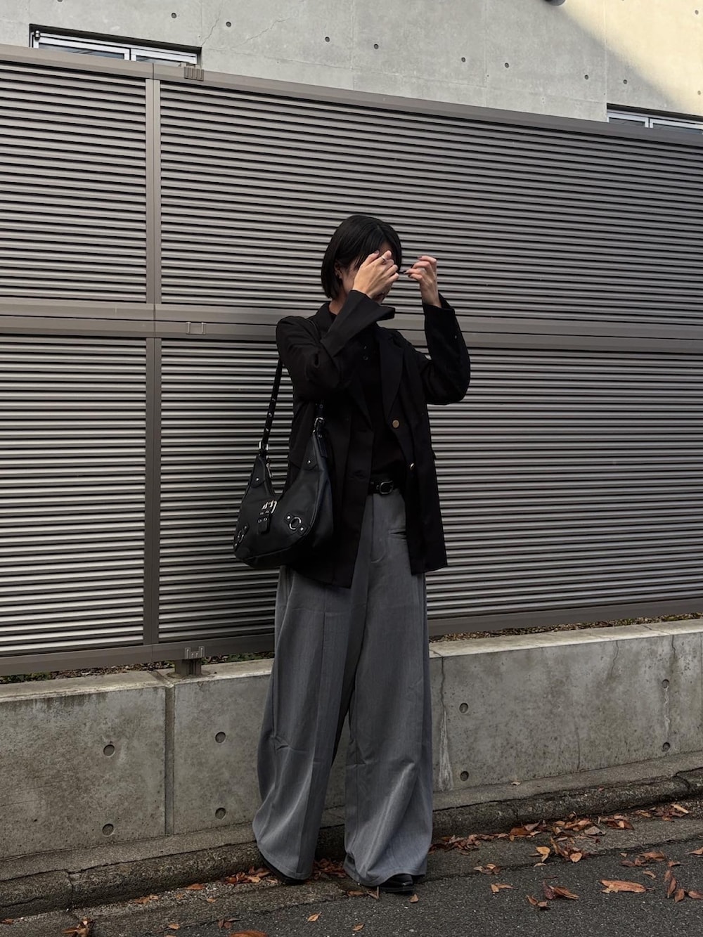 ブラック系のテーラードジャケット、ブラック系のニット/セーター、グレー系のスラックスを着用したレディースの冬コーディネートの2枚目の写真