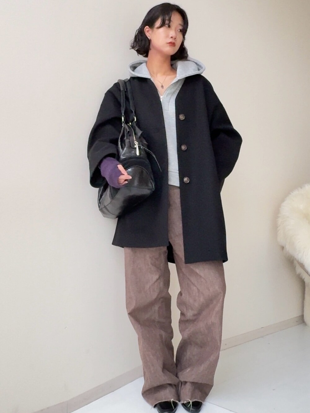 ブラック系のノーカラーコートを着用したレディースの秋コーディネートの2枚目の写真