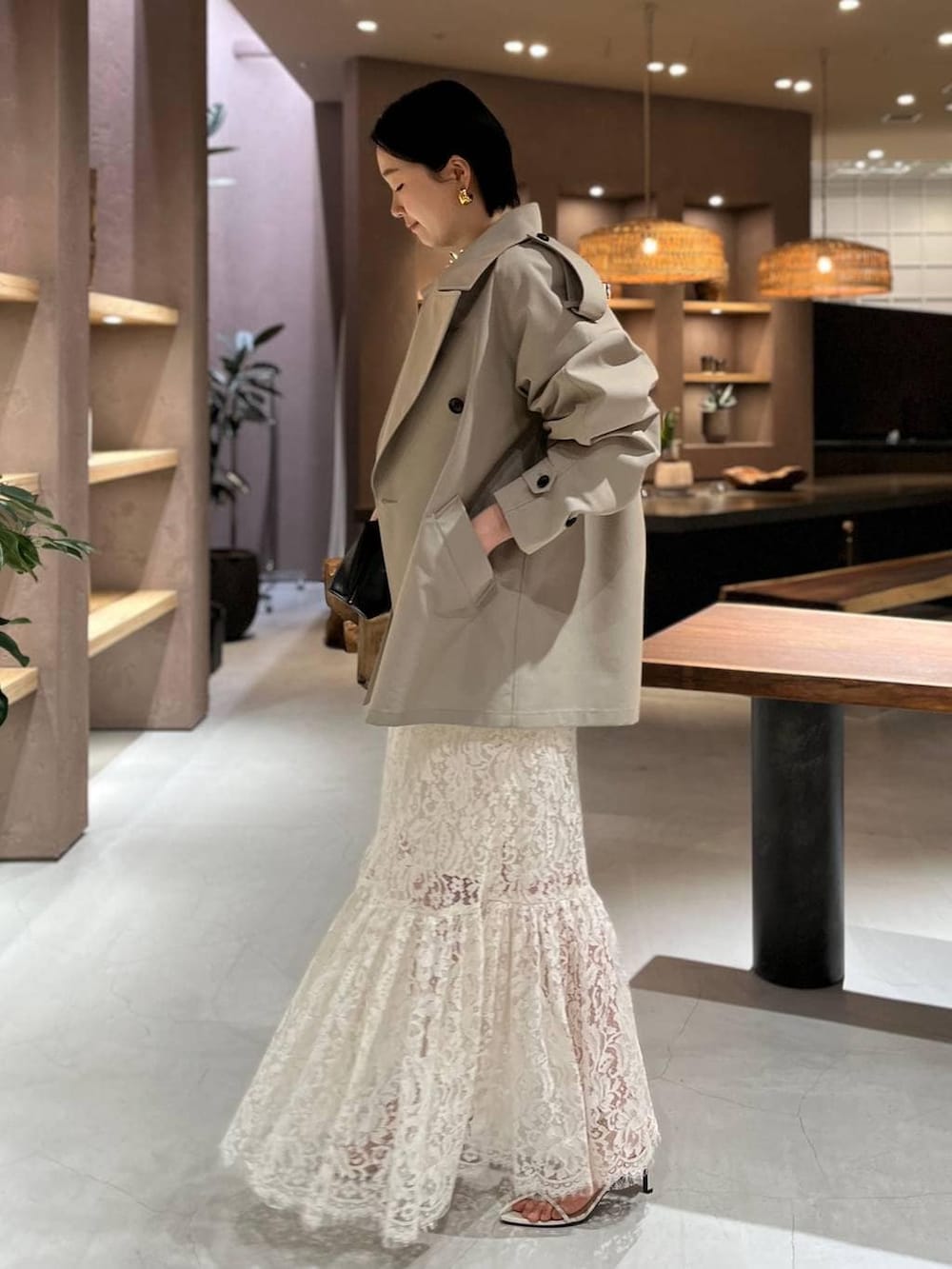 ベージュ系のトレンチコート、ホワイト系のスカート、ブラック系のニット/セーターを着用したレディースの冬コーディネートの3枚目の写真