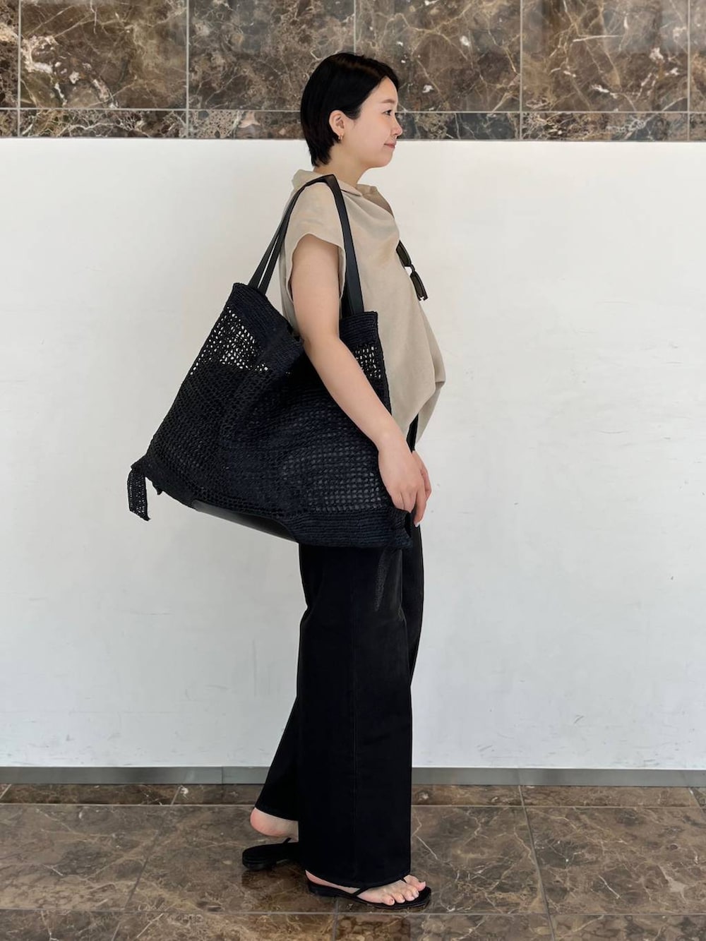 ベージュ系のシャツ/ブラウス、ブラック系のトートバッグ、ブラック系のサンダルを着用したレディースの春コーディネートの2枚目の写真