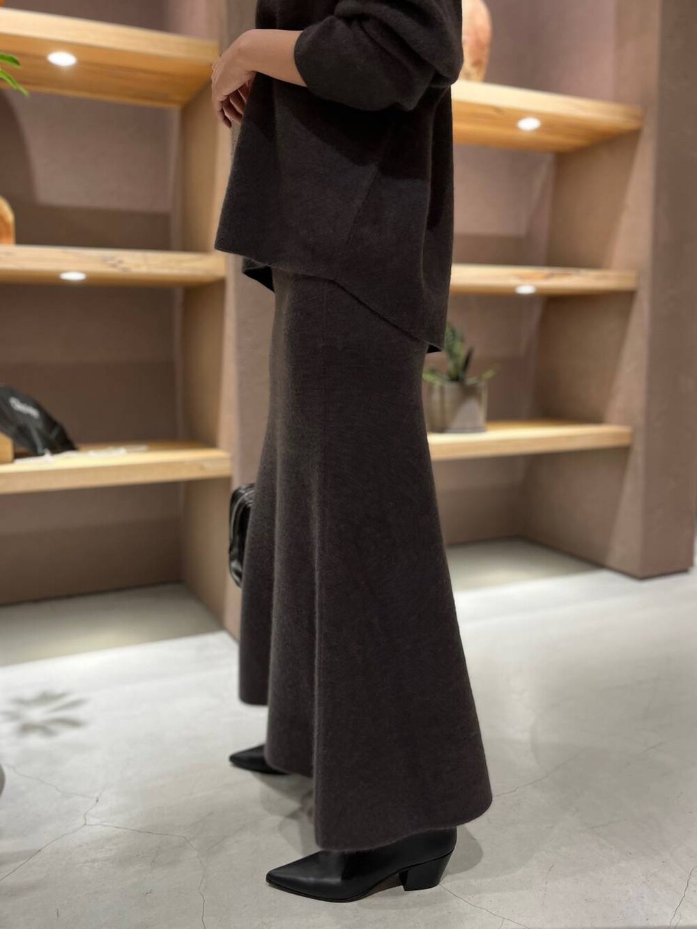 グレー系のニット/セーター、グレー系のスカートを着用したレディースの秋コーディネートの6枚目の写真