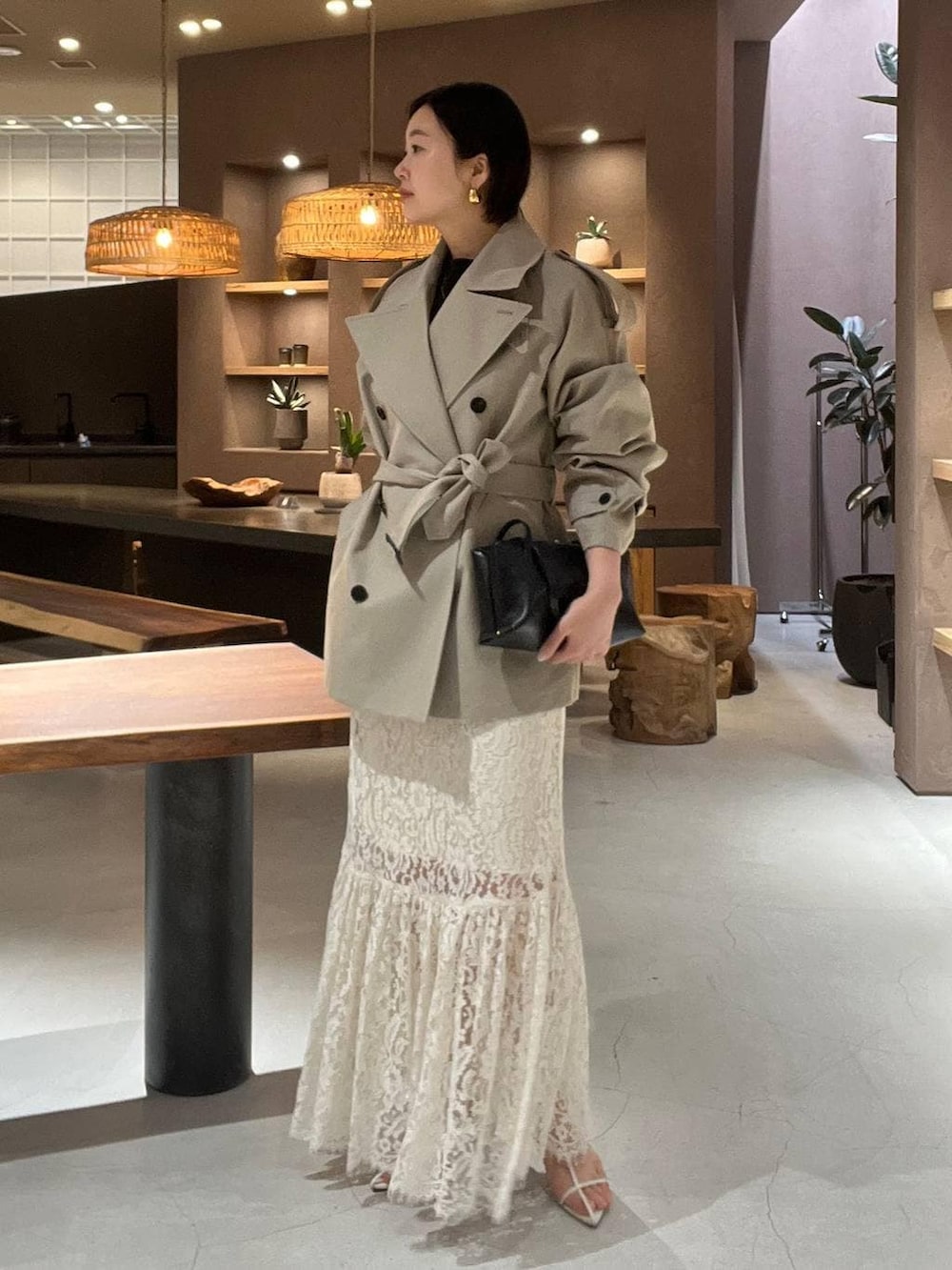 ベージュ系のトレンチコート、ホワイト系のスカート、ブラック系のニット/セーターを着用したレディースの冬コーディネートの2枚目の写真