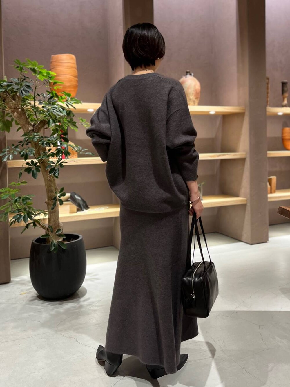 グレー系のニット/セーター、グレー系のスカートを着用したレディースの秋コーディネートの3枚目の写真