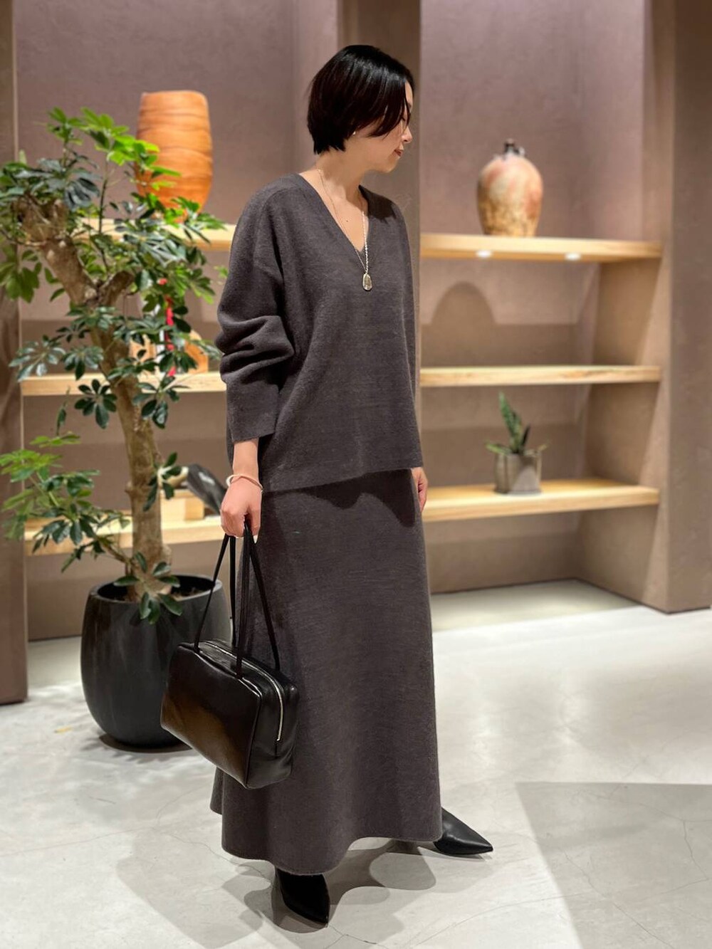 グレー系のニット/セーター、グレー系のスカートを着用したレディースの秋コーディネートの2枚目の写真