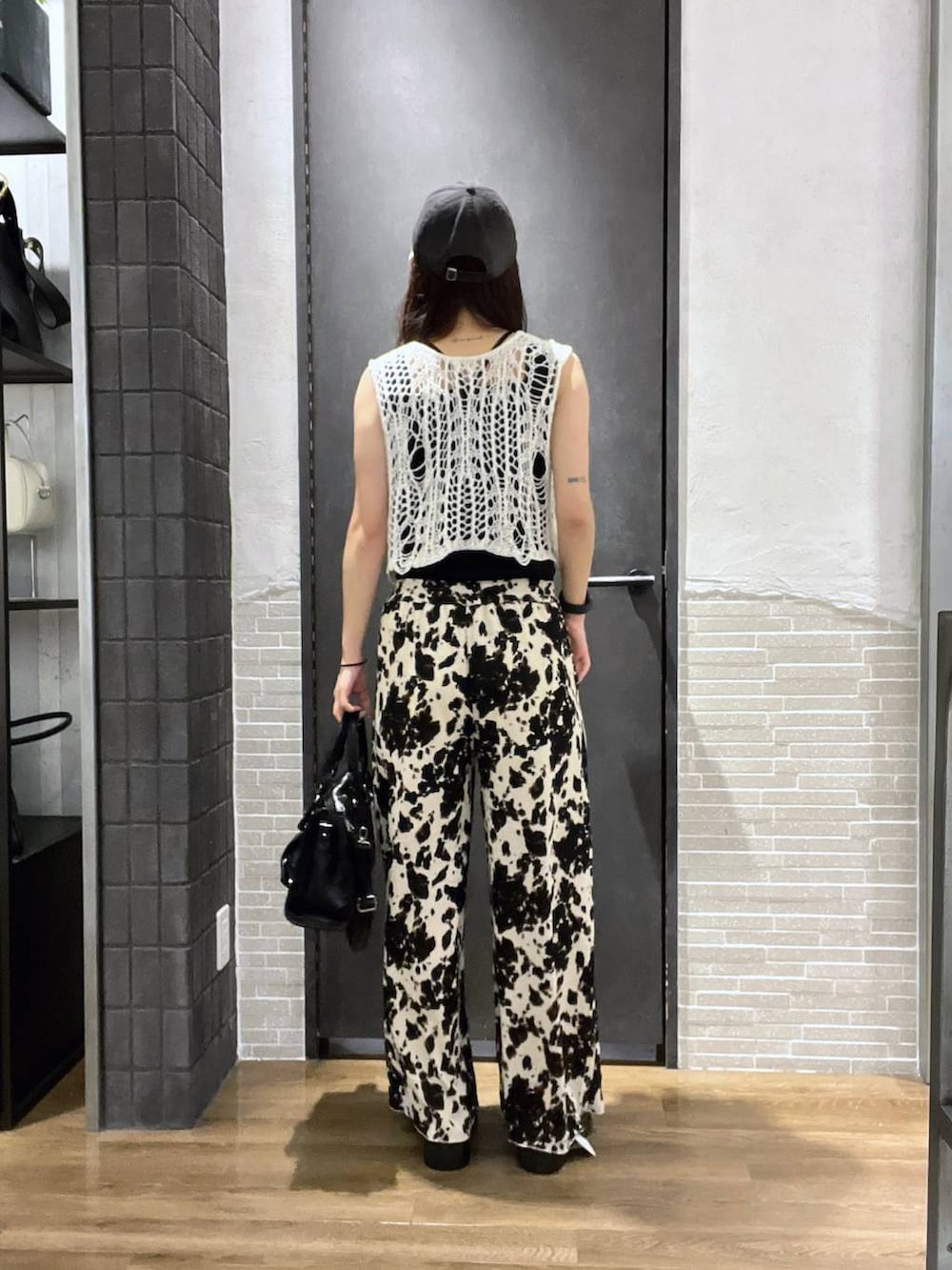 ホワイト系のベスト、ブラック系のタンクトップ、ブラック系のボストンバッグを着用したレディースの夏コーディネートの3枚目の写真