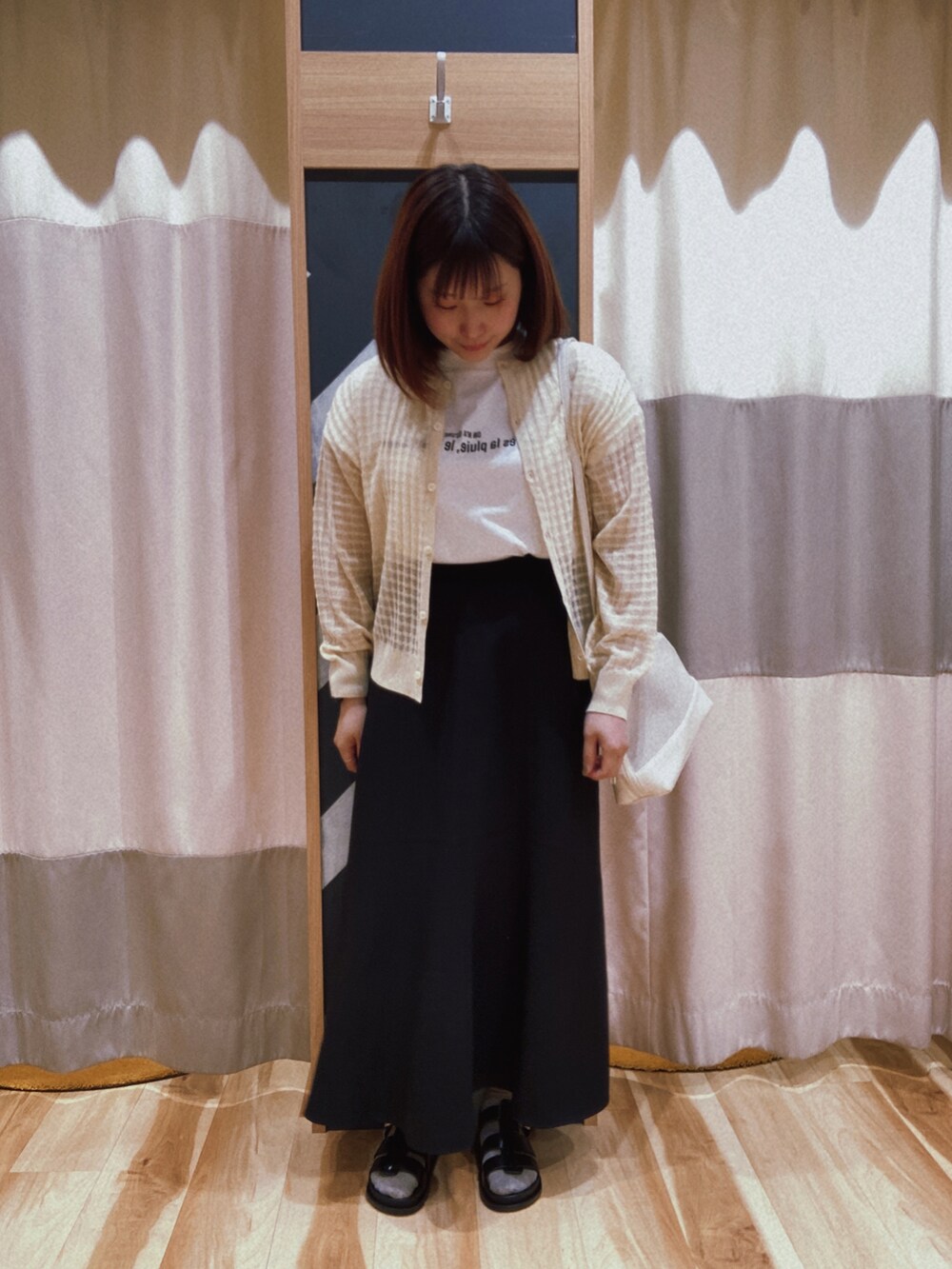 ブラック系のスカート、ホワイト系のバッグ、ホワイト系のTシャツ/カットソーを着用したレディースの春コーディネートの2枚目の写真