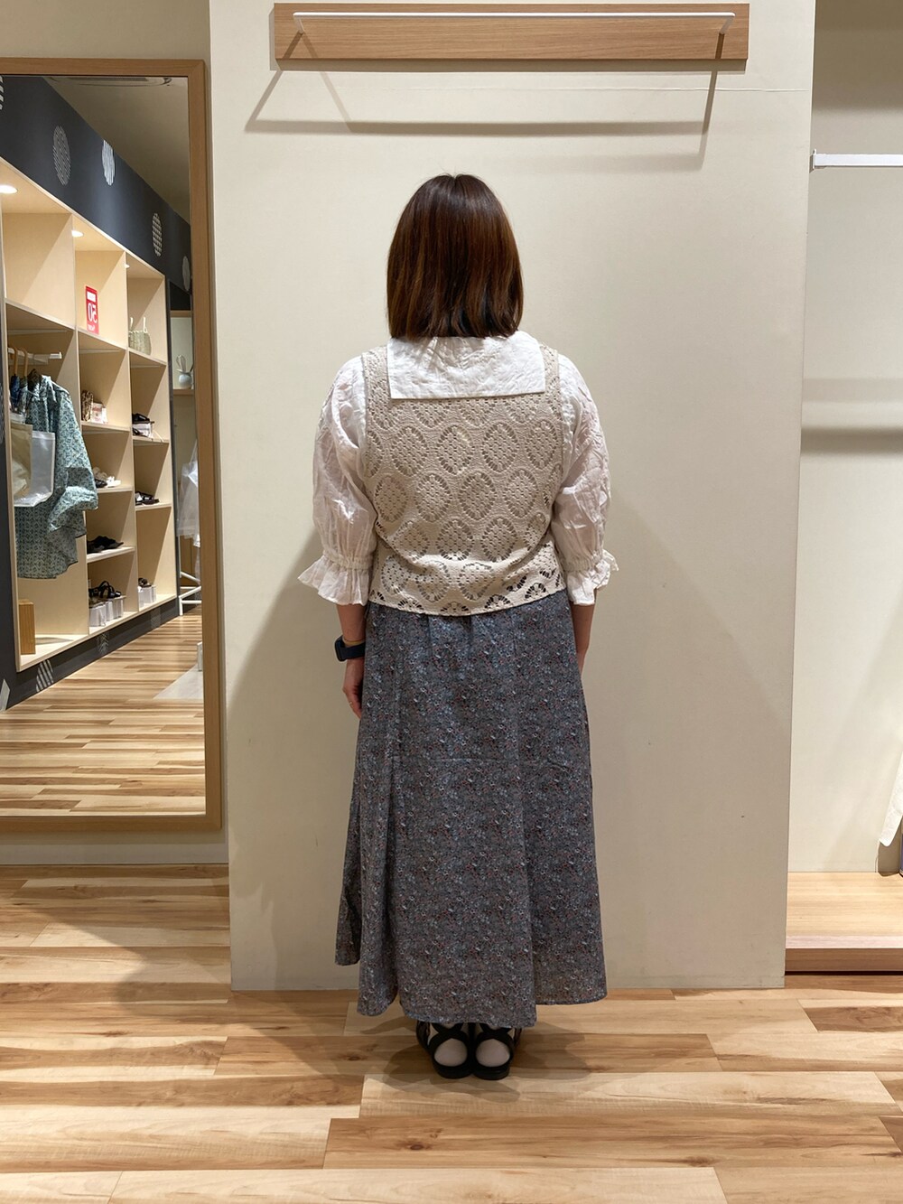 ブルー系のスカート、ホワイト系のベスト、ホワイト系のシャツ/ブラウスを着用したレディースの夏コーディネートの2枚目の写真