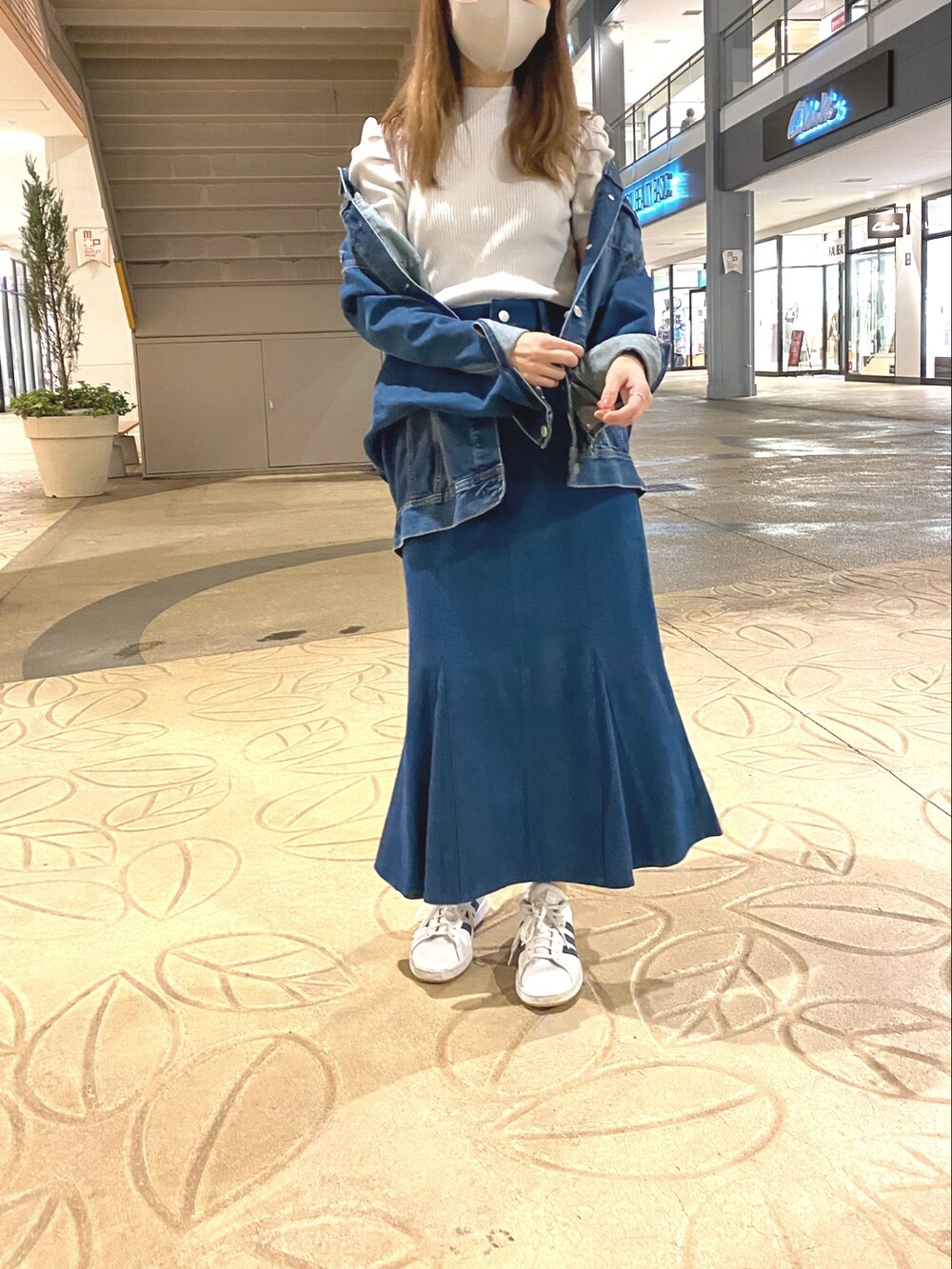 ブルー系のデニムスカート、ホワイト系のスニーカーを着用したレディースの春コーディネートの2枚目の写真
