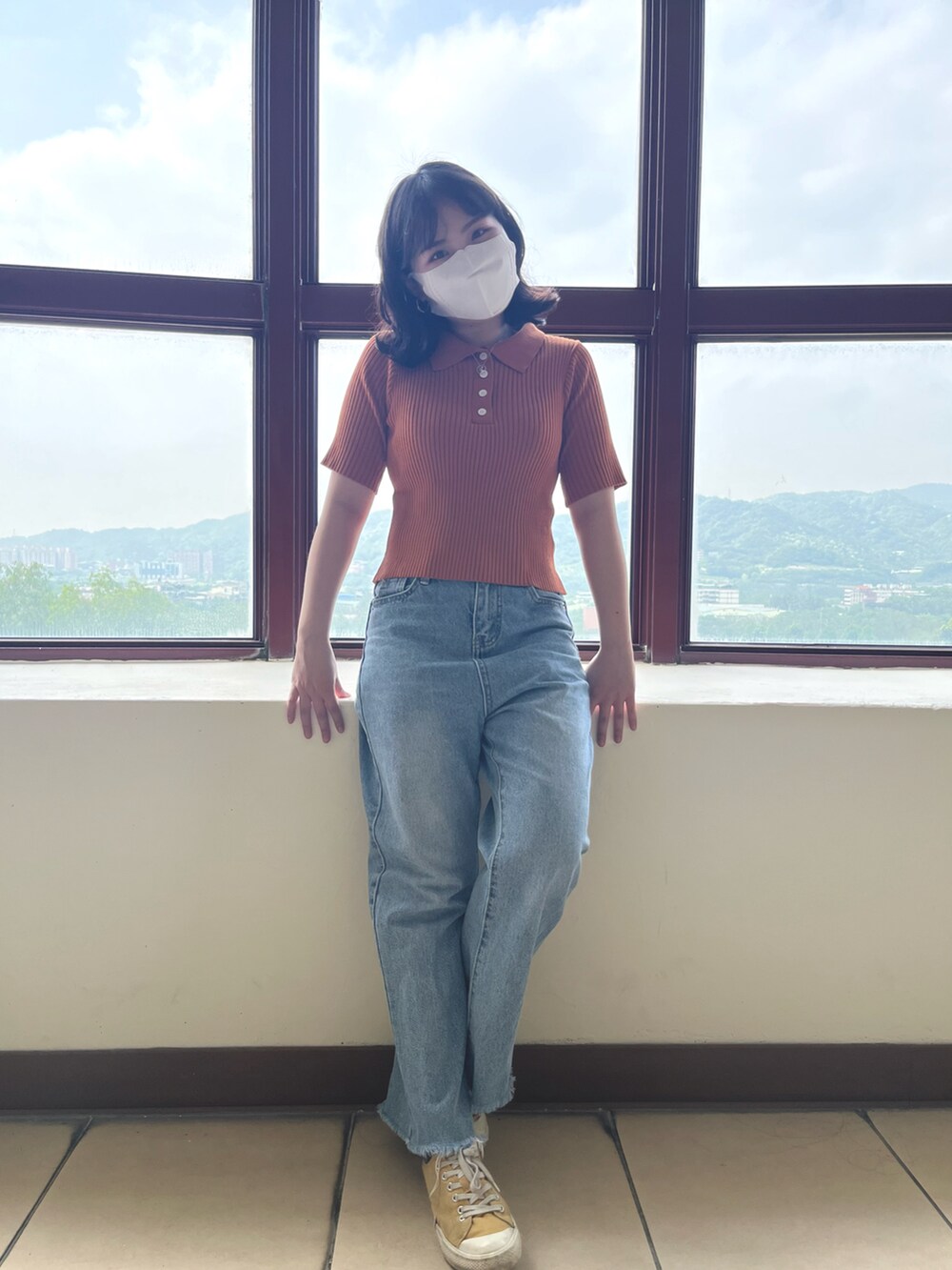 オレンジ系のトップスを着用したレディースの春コーディネートの2枚目の写真