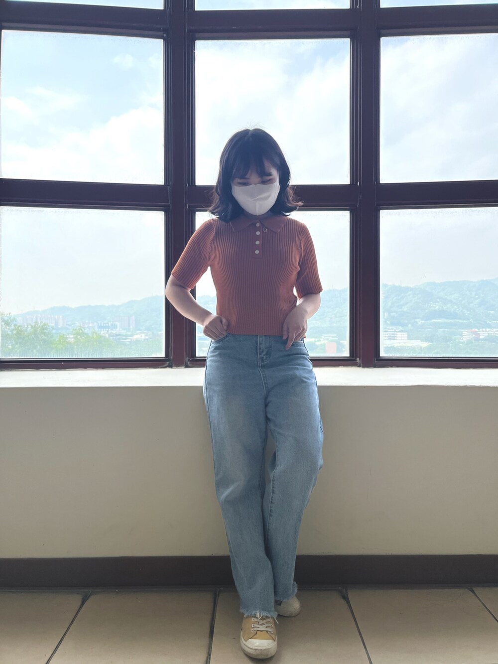 オレンジ系のトップスを着用したレディースの春コーディネートの3枚目の写真