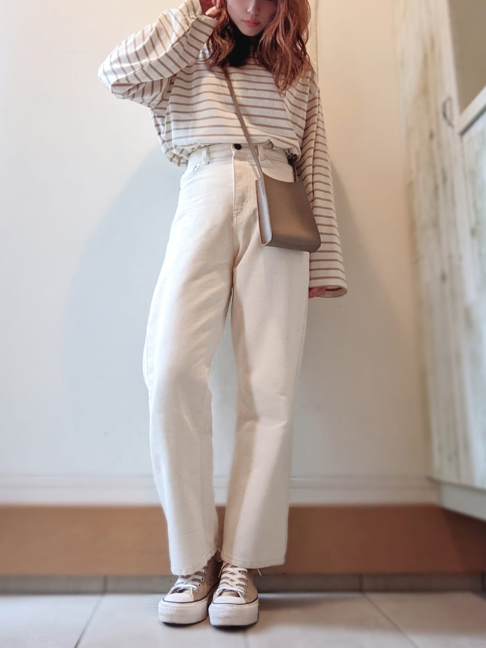 ベージュ系のTシャツ/カットソー、ベージュ系のショルダーバッグ、ベージュ系のスニーカーを着用したレディースの秋コーディネートの2枚目の写真