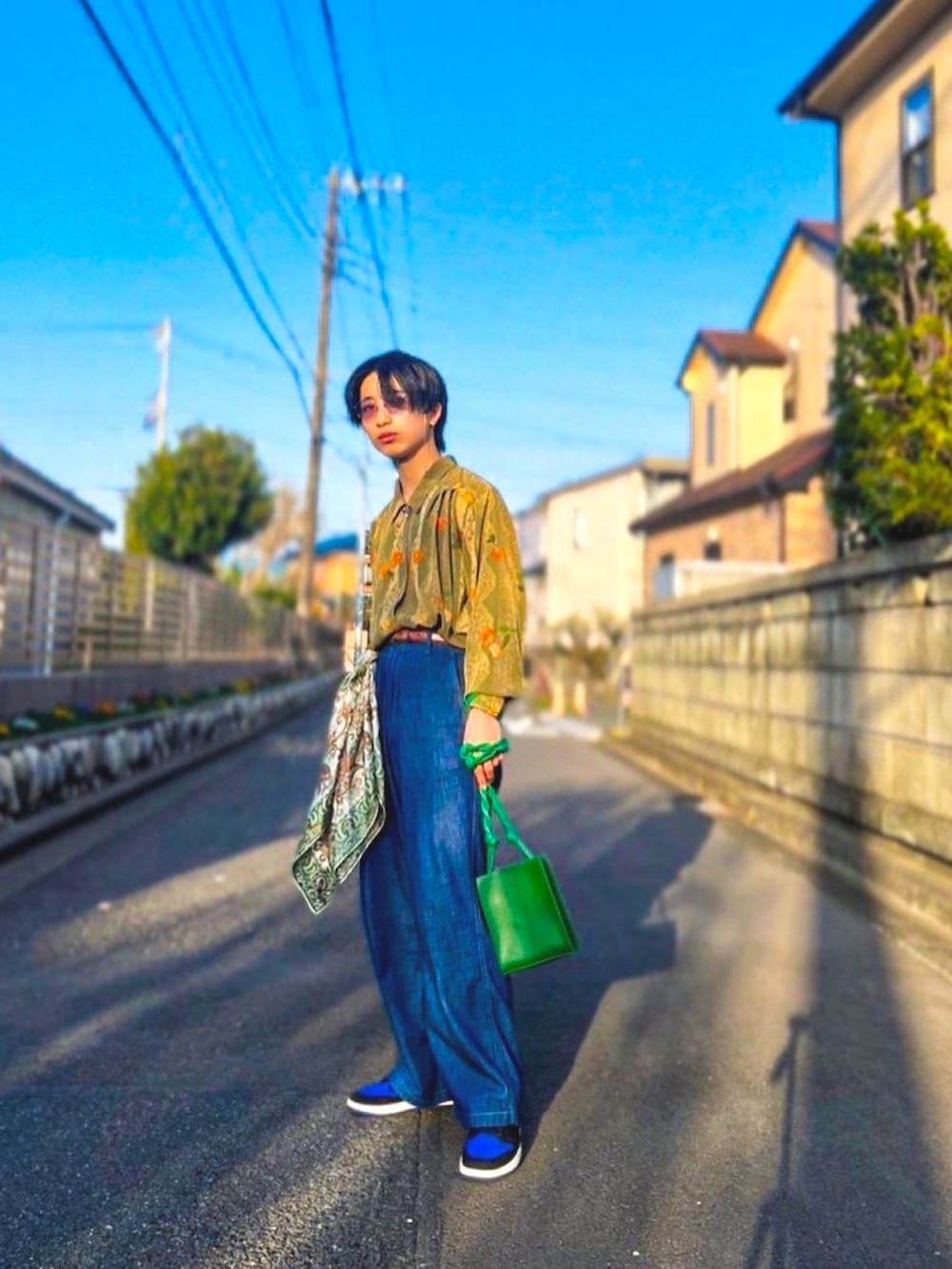 ブルー系のスニーカー、グリーン系のショルダーバッグ、ブルー系のデニムパンツを着用したメンズの春コーディネートの2枚目の写真