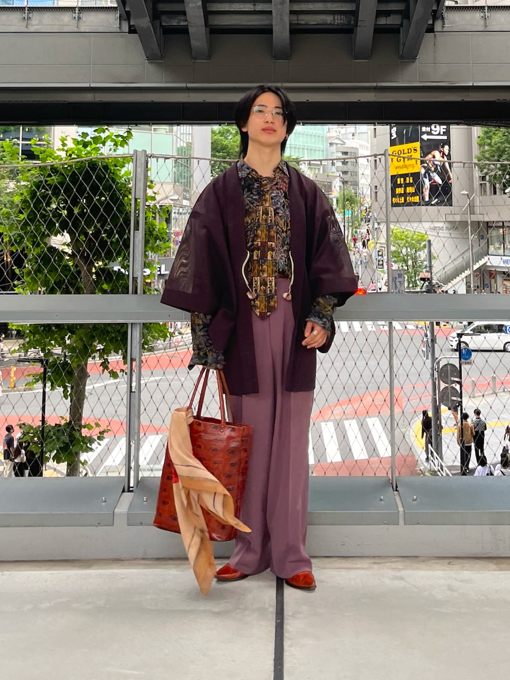 パープル系のスラックス、オレンジ系のトートバッグ、オレンジ系のブーツを着用したメンズの夏コーディネートの4枚目の写真