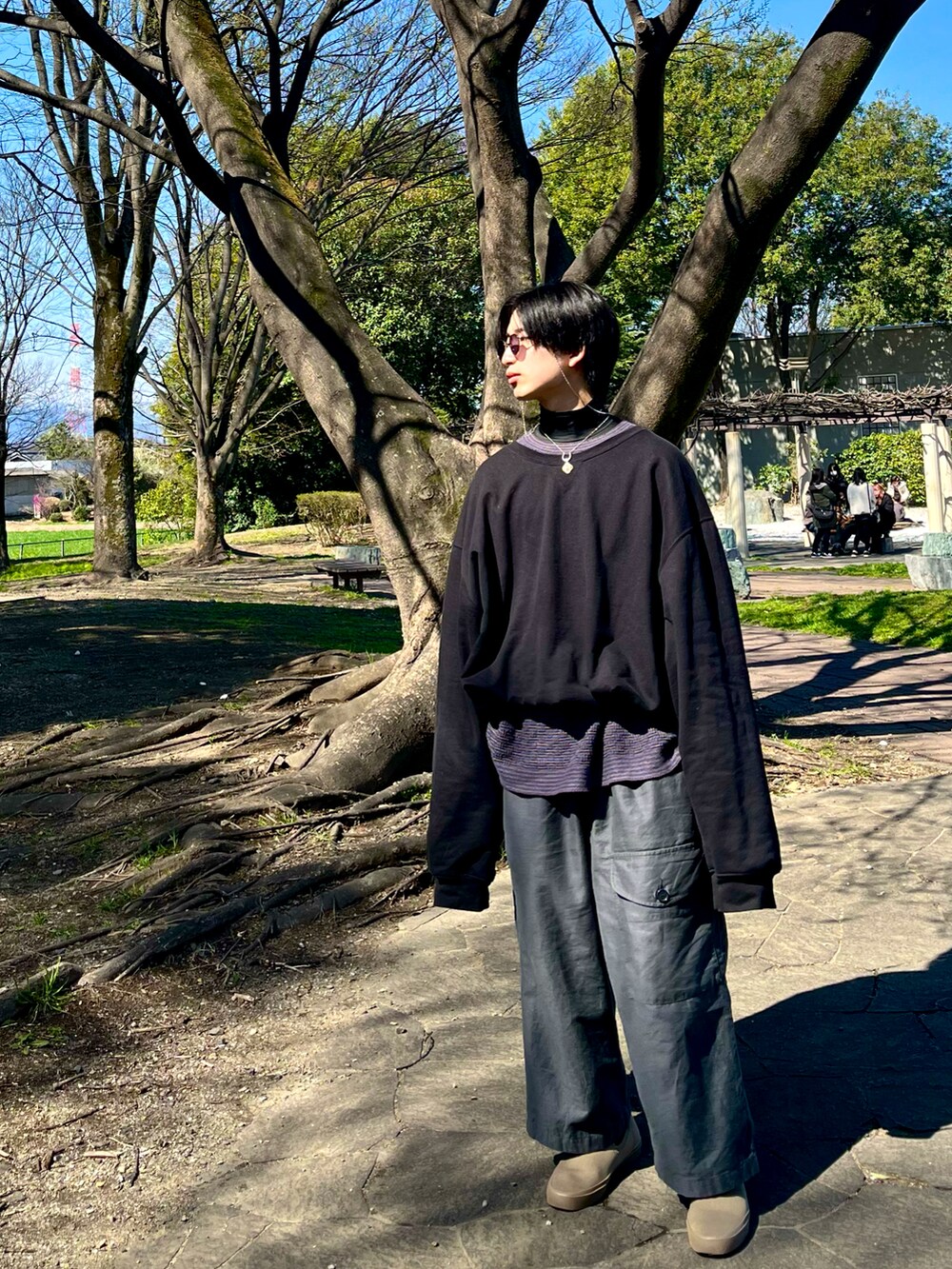 グレー系のカーゴパンツ、ベージュ系のスリッポン、ブラック系のスウェットを着用したメンズの春コーディネートの3枚目の写真