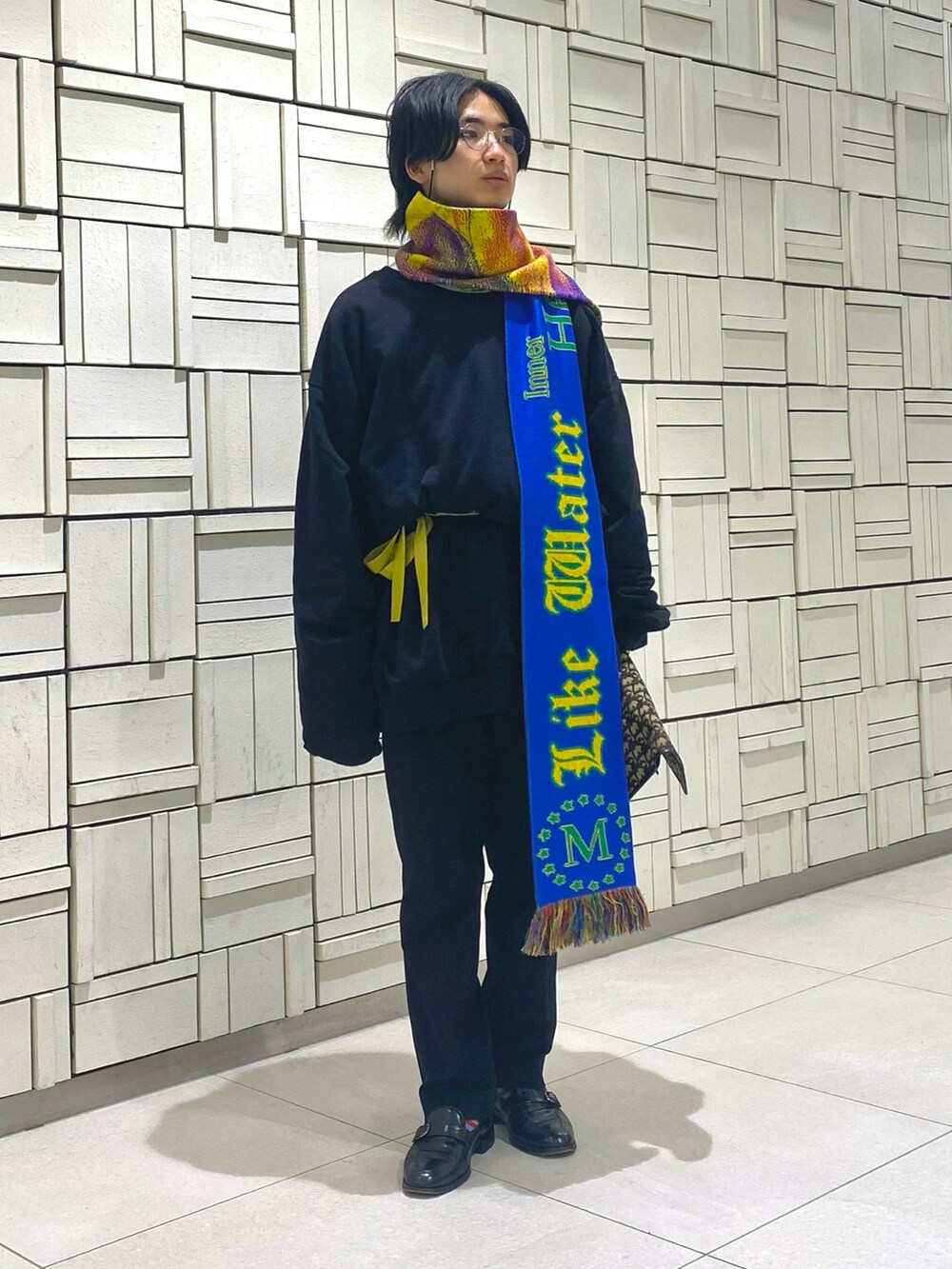 ブラック系のスウェット、ゴールド系のクラッチバッグ、ブラック系のスラックスを着用したメンズの冬コーディネートの2枚目の写真