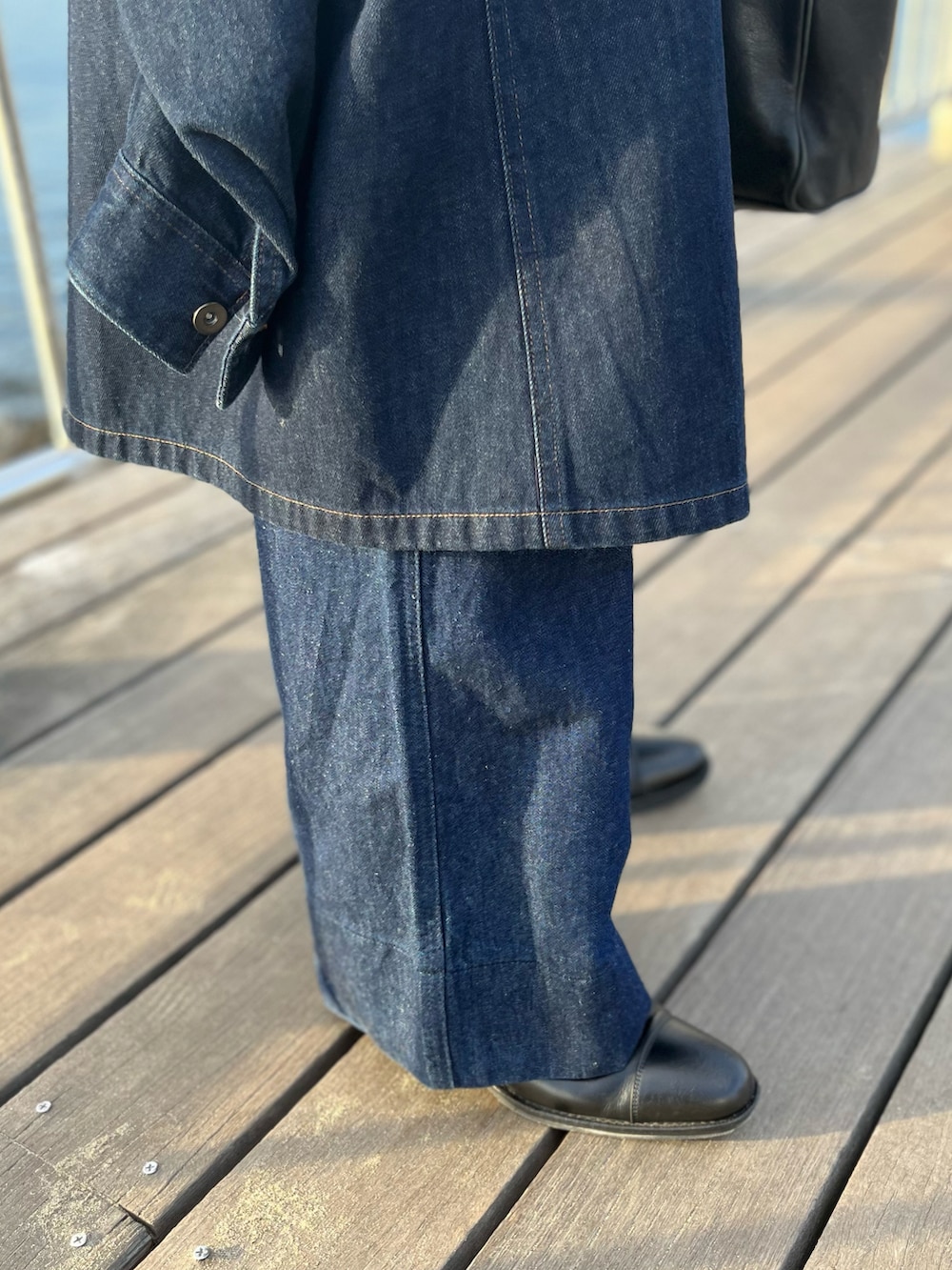 ブルー系のステンカラーコート、ブラック系のタンクトップ、ブラック系のトートバッグを着用したメンズの夏コーディネートの4枚目の写真