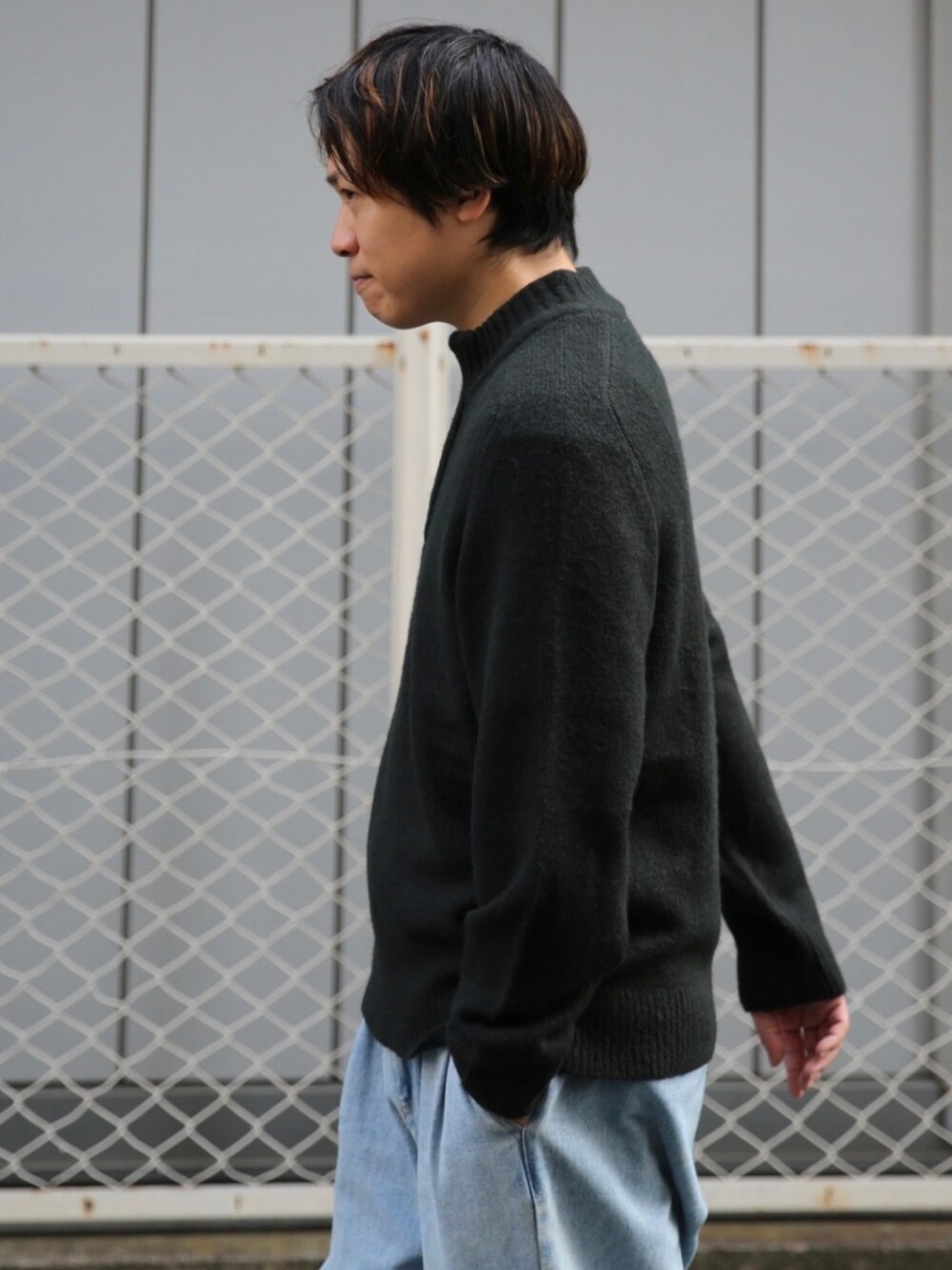 ブラック系のニット/セーター、ブルー系のデニムパンツ、ブラック系のスニーカーを着用したメンズの秋コーディネートの2枚目の写真