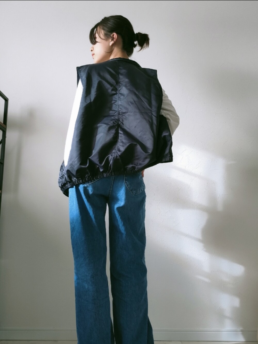 ブルー系のデニムパンツ、ブラック系のベスト、ホワイト系のTシャツ/カットソーを着用したレディースの春コーディネートの3枚目の写真