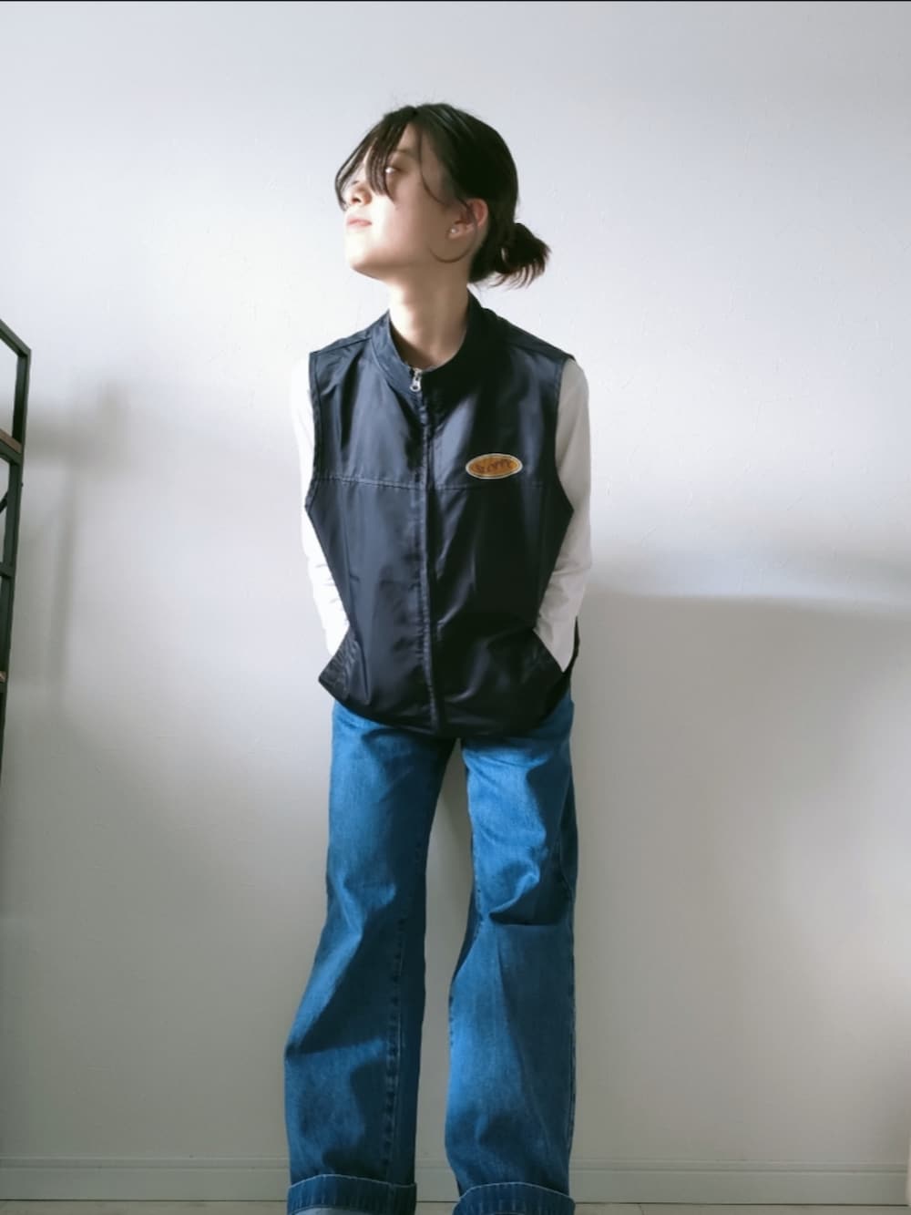 ブルー系のデニムパンツ、ブラック系のベスト、ホワイト系のTシャツ/カットソーを着用したレディースの春コーディネートの2枚目の写真