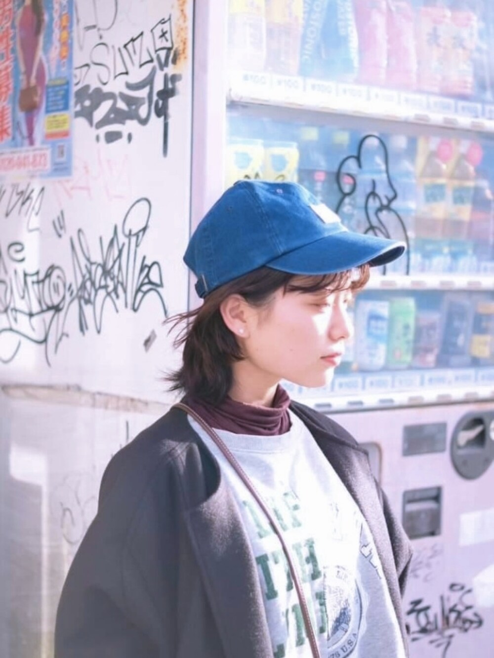 ブラック系のノーカラーコート、ブルー系のデニムパンツ、イエロー系のパンプスを着用したレディースの冬コーディネートの2枚目の写真