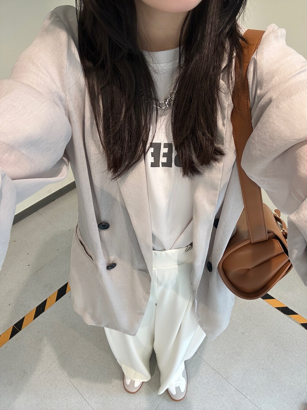 ホワイト系のスラックス、ベージュ系のテーラードジャケット、グレー系のシャツ/ブラウスを着用したレディースの夏コーディネートの4枚目の写真
