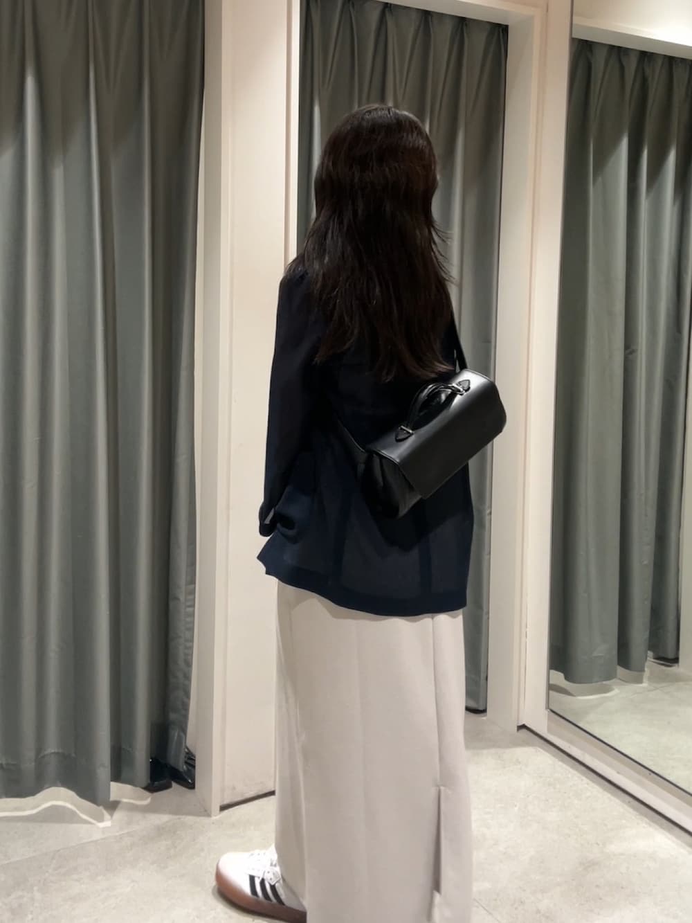 ホワイト系のスニーカー、ベージュ系のワンピース、ブラック系のショルダーバッグを着用したレディースの夏コーディネートの2枚目の写真