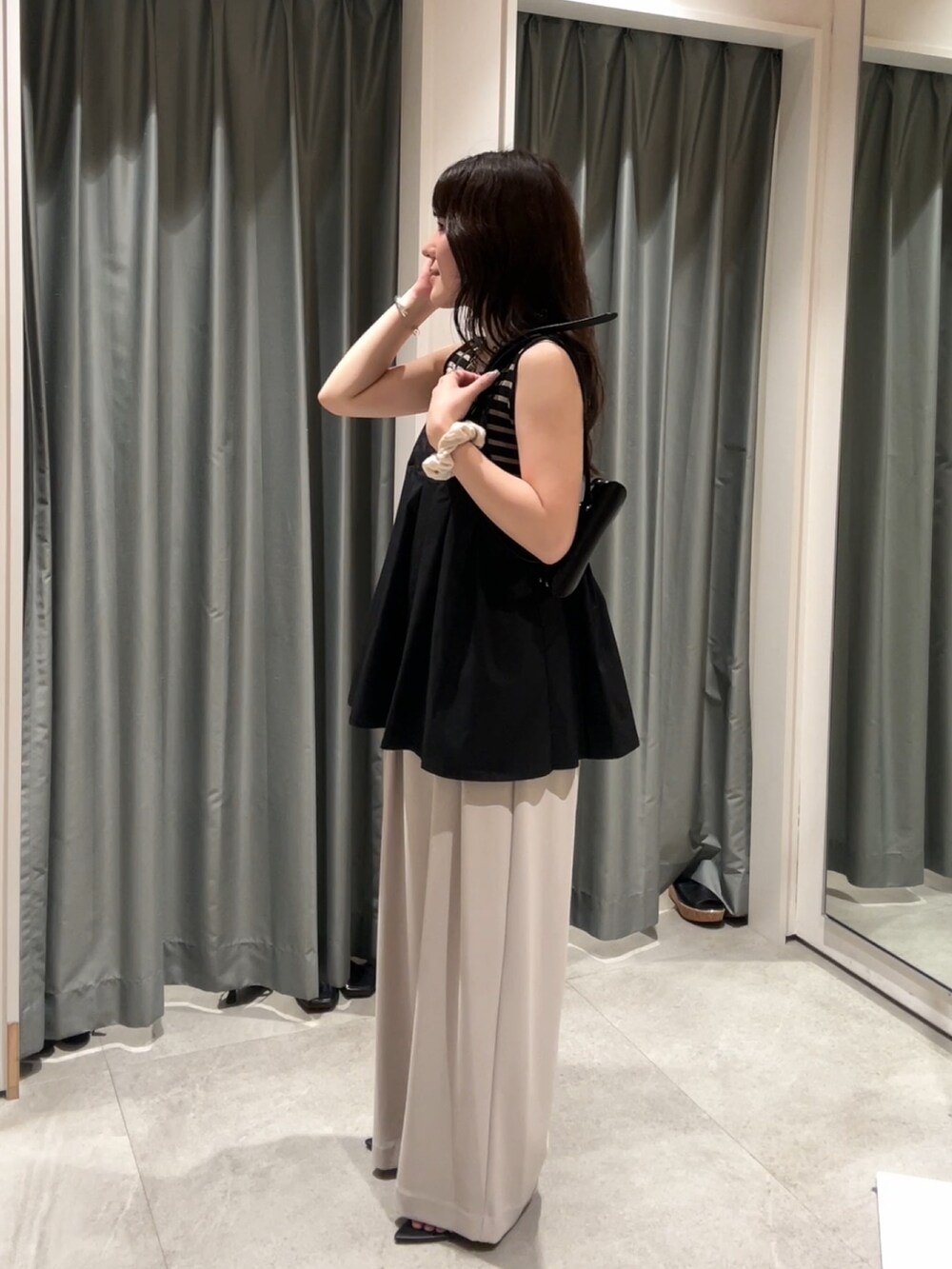 グレー系のスラックス、ブラック系のシャツ/ブラウス、ブラック系のショルダーバッグを着用したレディースの夏コーディネートの2枚目の写真