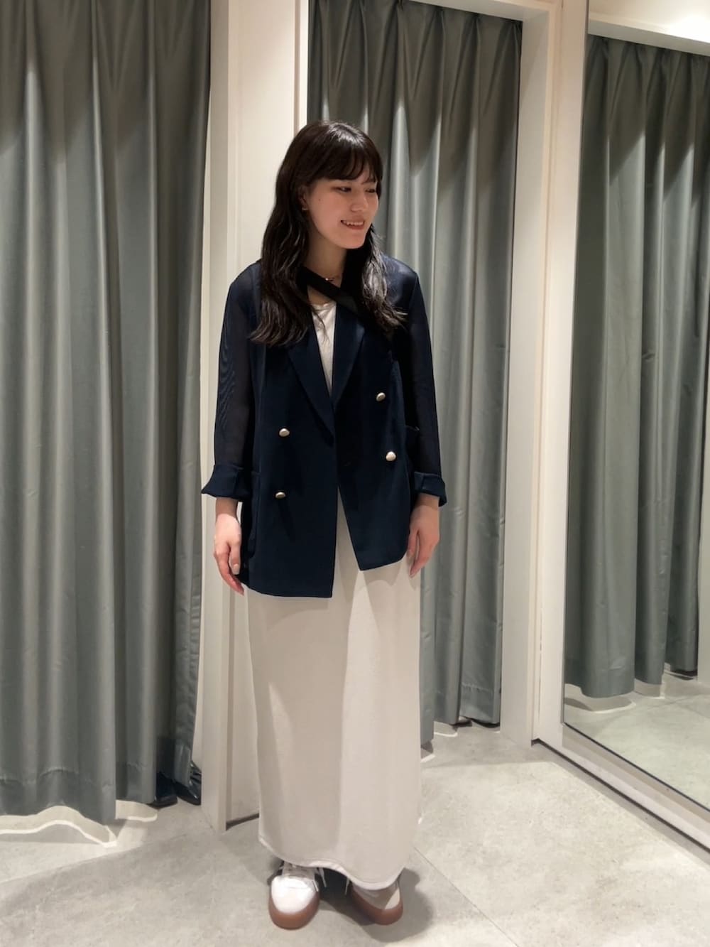 ホワイト系のスニーカー、ベージュ系のワンピース、ブラック系のショルダーバッグを着用したレディースの夏コーディネートの3枚目の写真