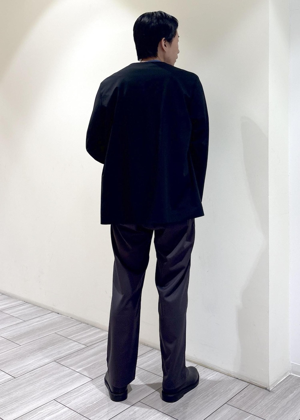 ブラック系のノーカラージャケット、ブルー系のニット/セーター、グレー系のその他パンツを着用したメンズの秋コーディネートの3枚目の写真