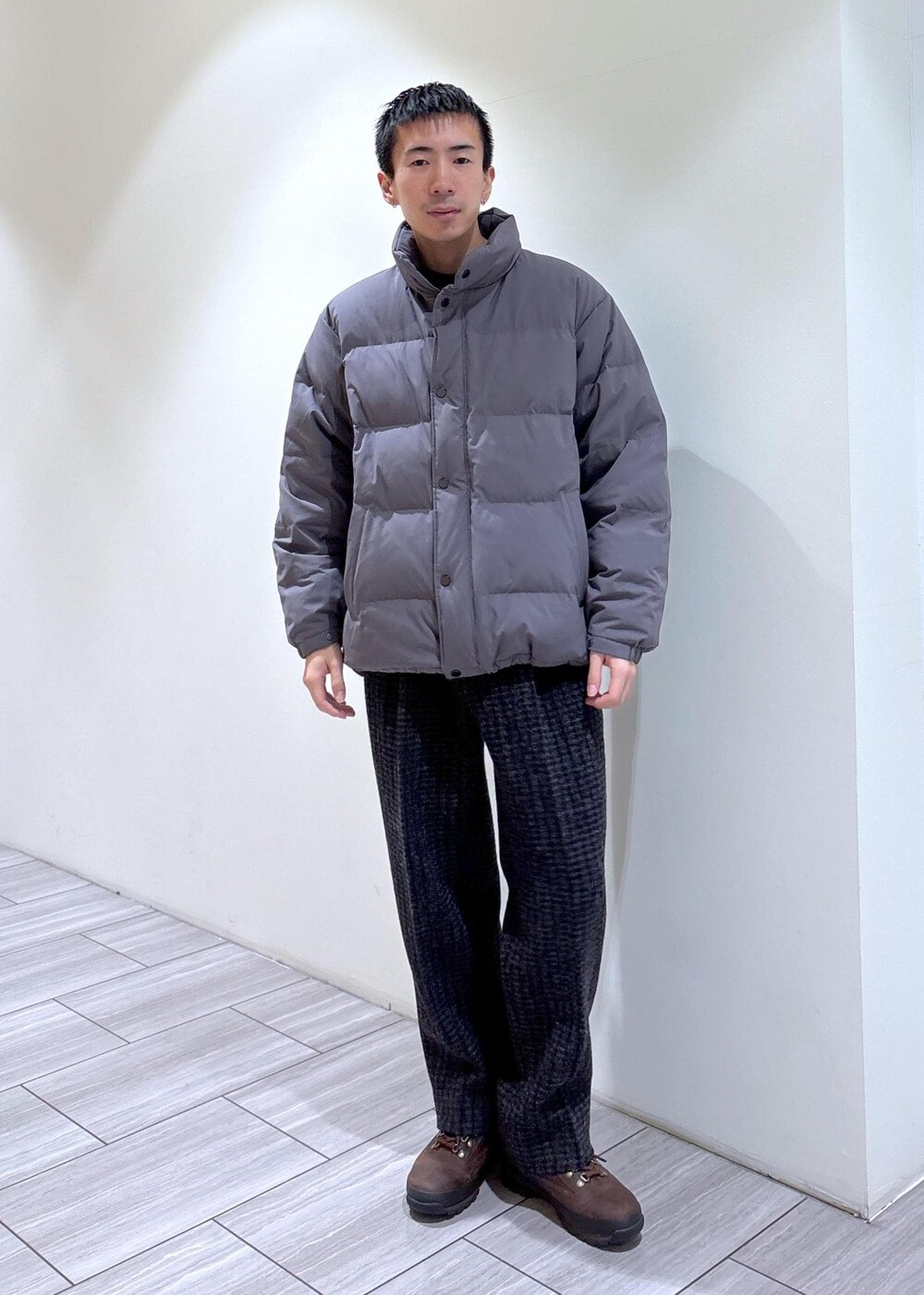 グレー系のダウンジャケット/コート、グレー系のスラックス、ブラウン系のブーツを着用したメンズの冬コーディネートの2枚目の写真