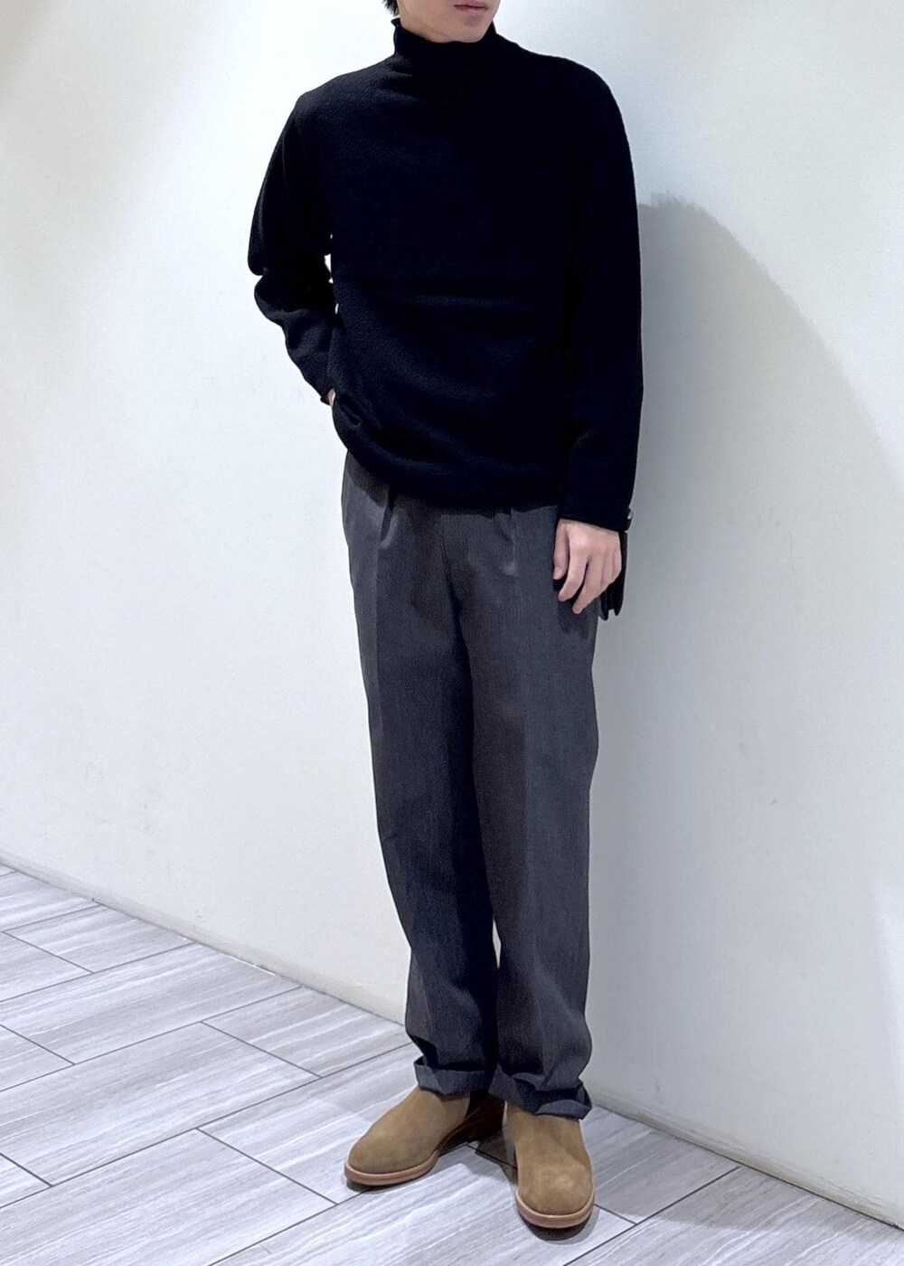 ブラック系のニット/セーター、グレー系のスラックスを着用したメンズの秋コーディネートの2枚目の写真