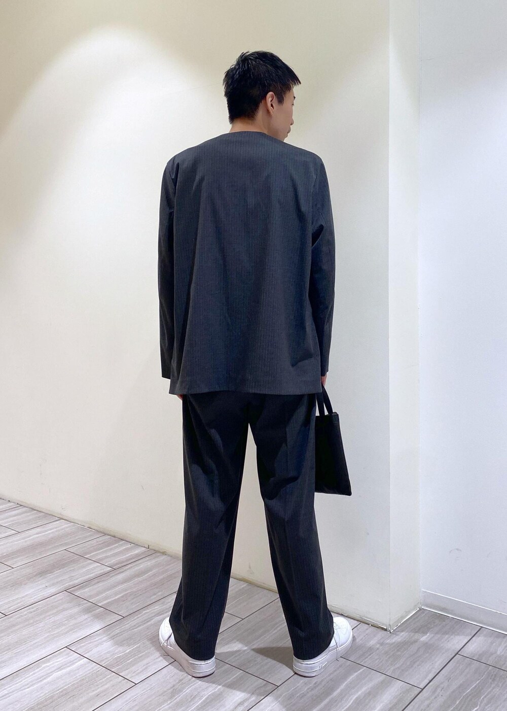 グレー系のノーカラージャケット、グレー系のスラックス、ホワイト系のスニーカーを着用したメンズの秋コーディネートの4枚目の写真