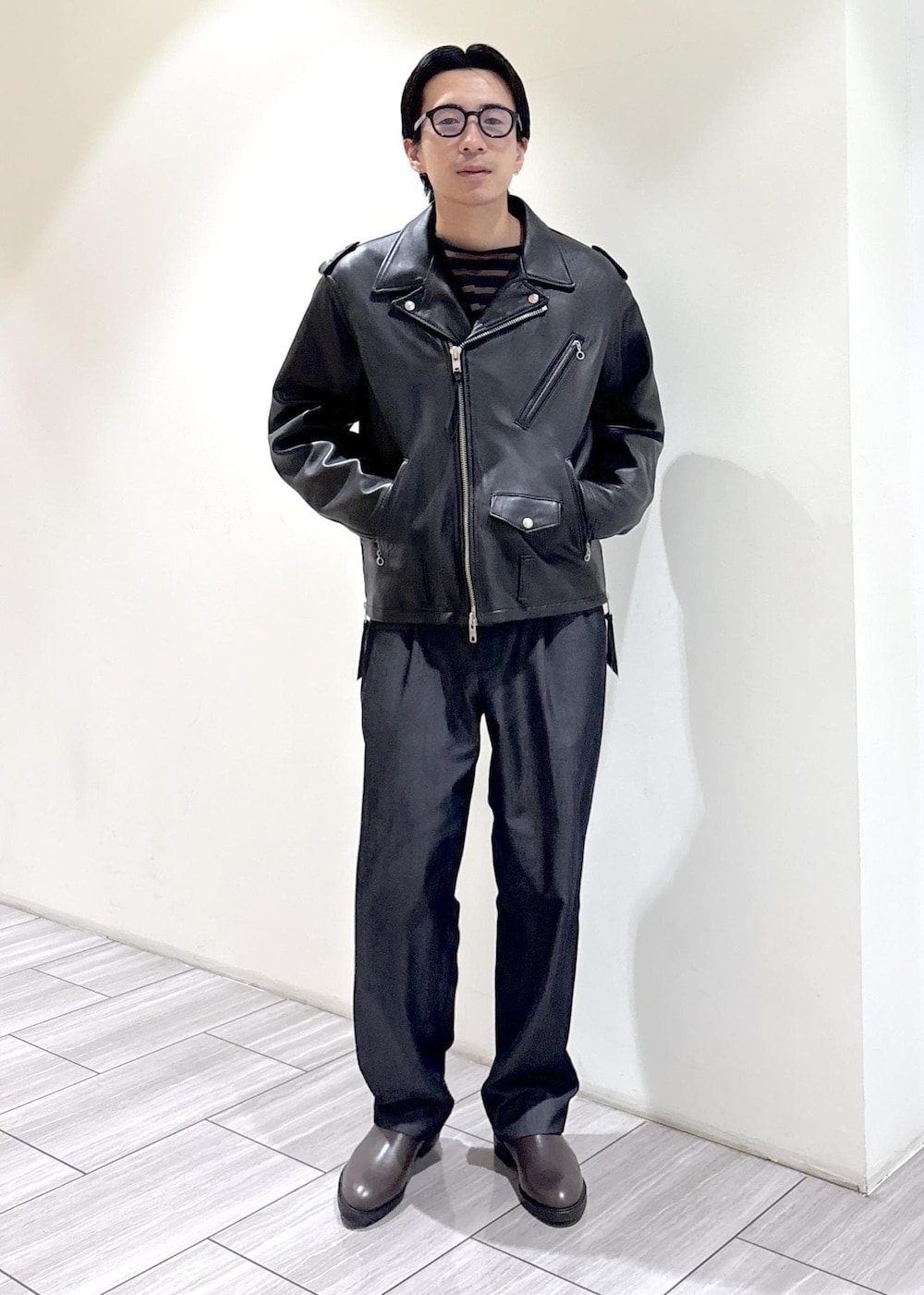 ブラック系のデニムパンツ、ブラウン系のTシャツ/カットソー、ブラック系のライダースジャケットを着用したメンズの秋コーディネートの2枚目の写真