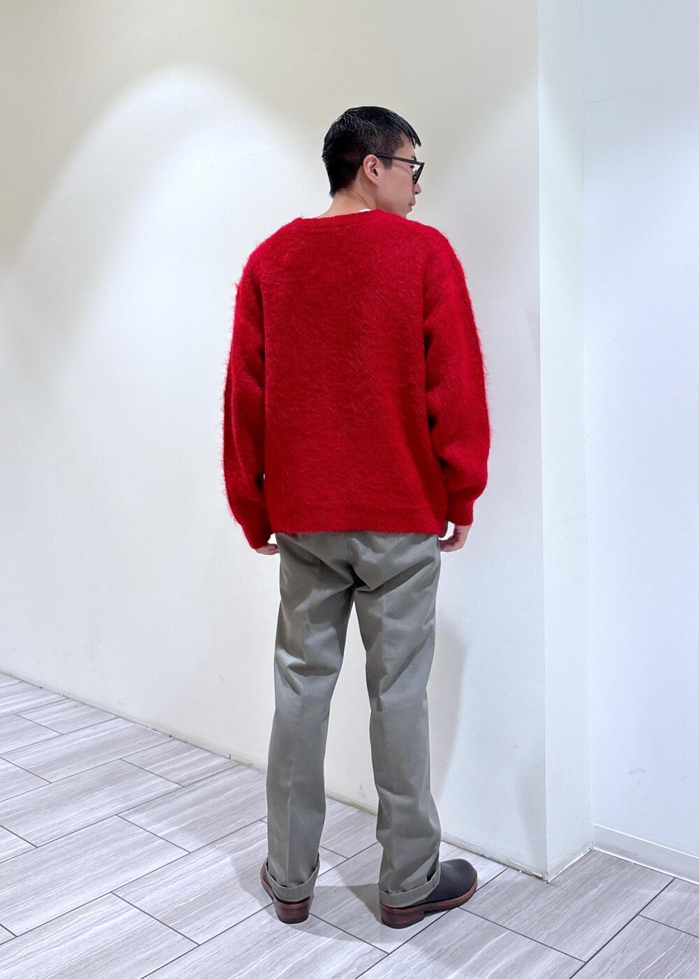 レッド系のニット/セーター、ブラック系のブーツ、グレー系のその他パンツを着用したメンズの秋コーディネートの4枚目の写真