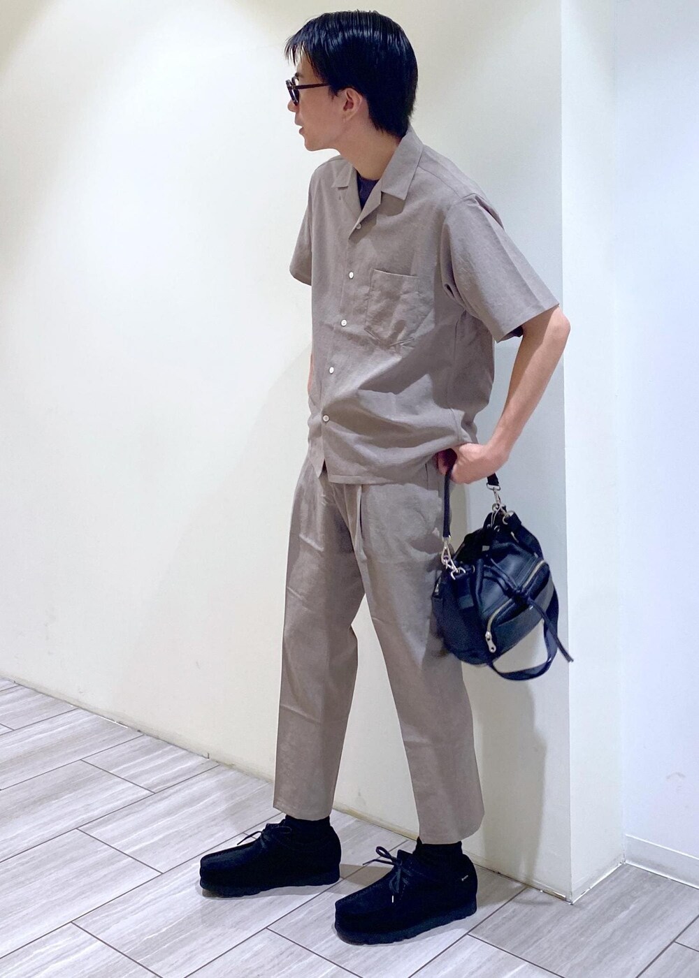 ベージュ系のセットアップ、ブラック系のTシャツ/カットソー、ブラック系のブーツを着用したメンズの夏コーディネートの2枚目の写真
