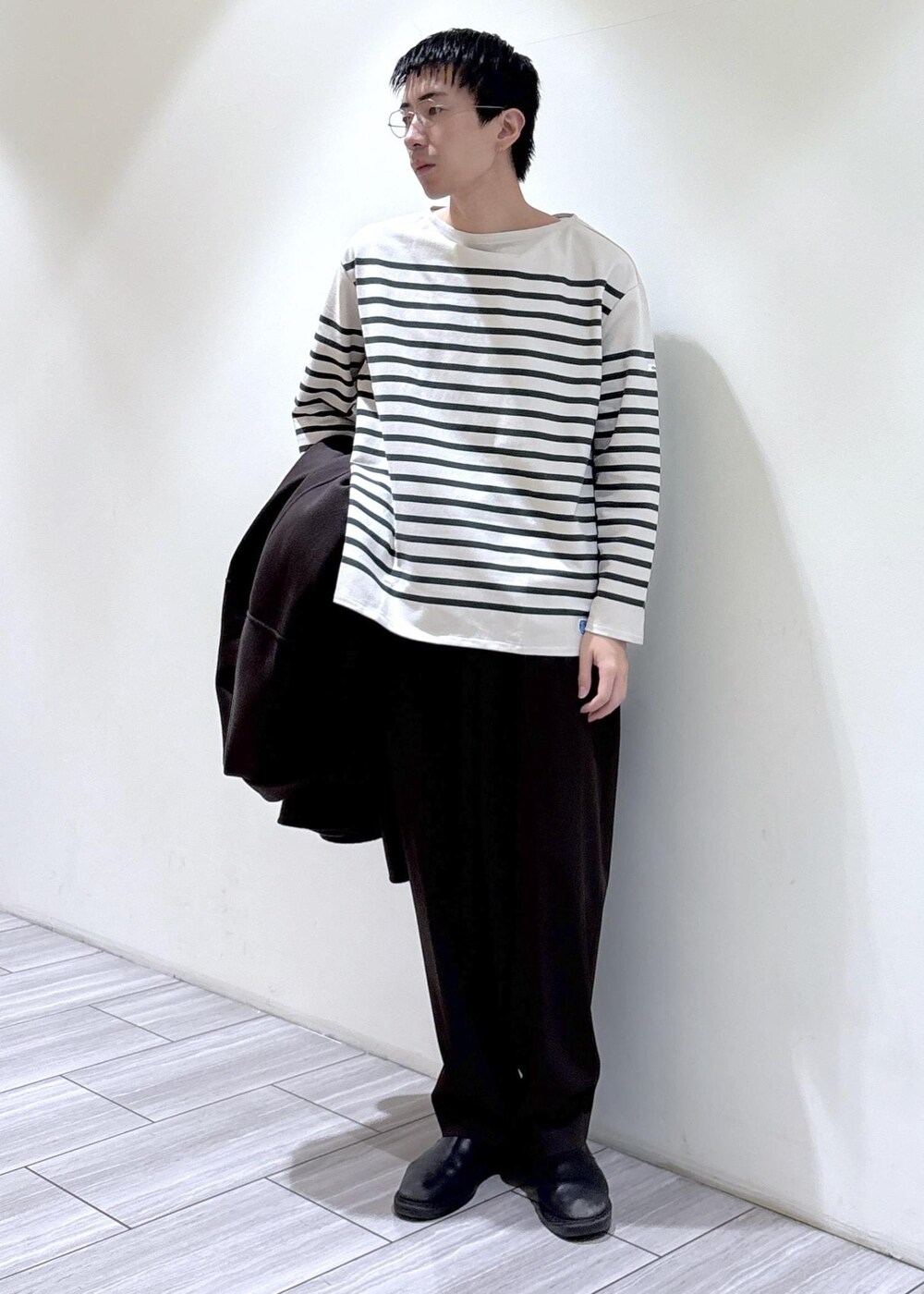 ブラウン系のスラックス、ブラウン系のステンカラーコート、ホワイト系のTシャツ/カットソーを着用したメンズの秋コーディネートの4枚目の写真