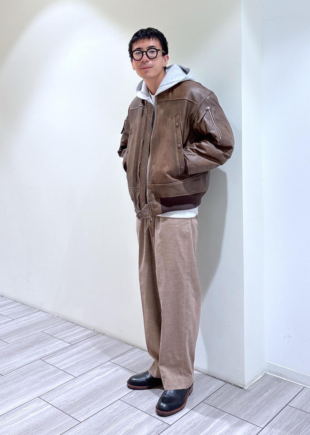 ブラック系のブーツ、グレー系のパーカー、ベージュ系のスラックスを着用したメンズの秋コーディネートの2枚目の写真