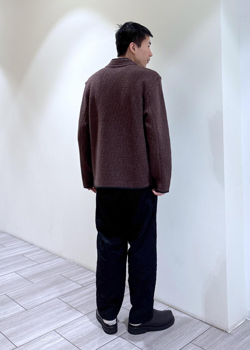 ブラック系のスラックス、ブラウン系のカーディガン/ボレロを着用したメンズの冬コーディネートの3枚目の写真