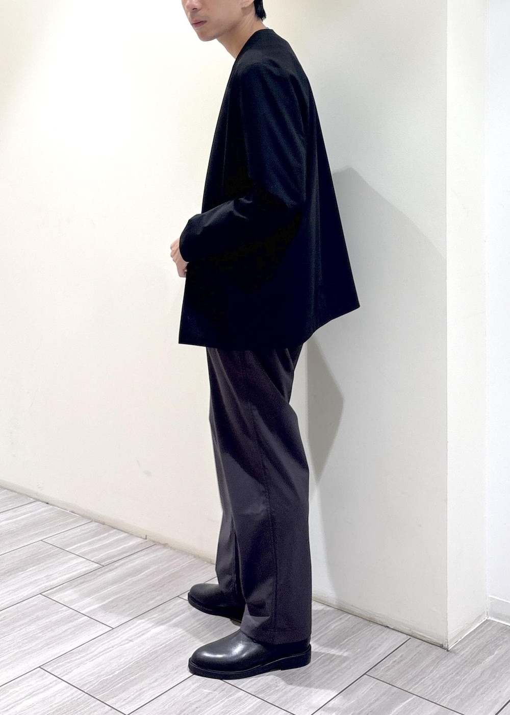 ブラック系のノーカラージャケット、ブルー系のニット/セーター、グレー系のその他パンツを着用したメンズの秋コーディネートの2枚目の写真