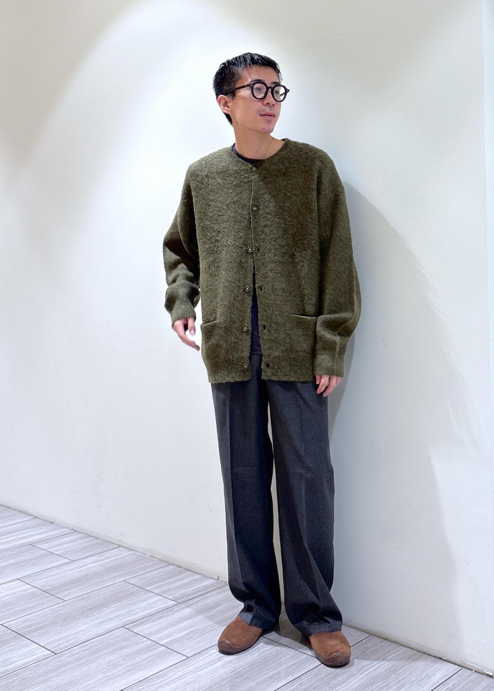 グリーン系のカーディガン/ボレロ、ブラウン系のスリッポン、グレー系のスラックスを着用したメンズの秋コーディネートの4枚目の写真