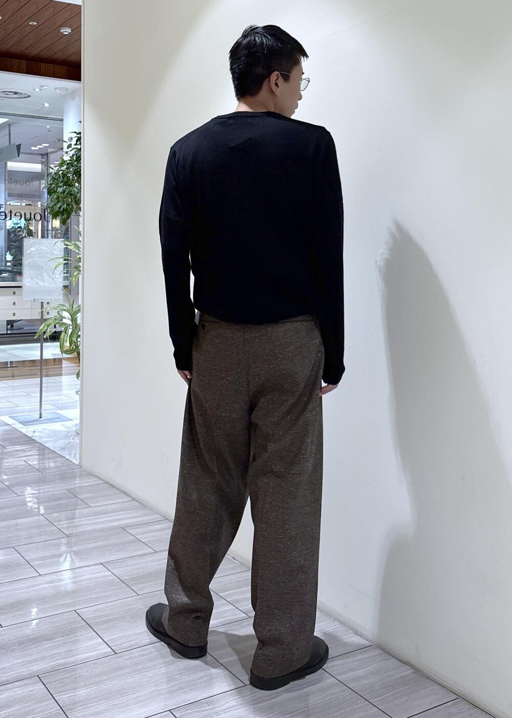 ブラック系のニット/セーター、ブラウン系のスラックスを着用したメンズの秋コーディネートの3枚目の写真