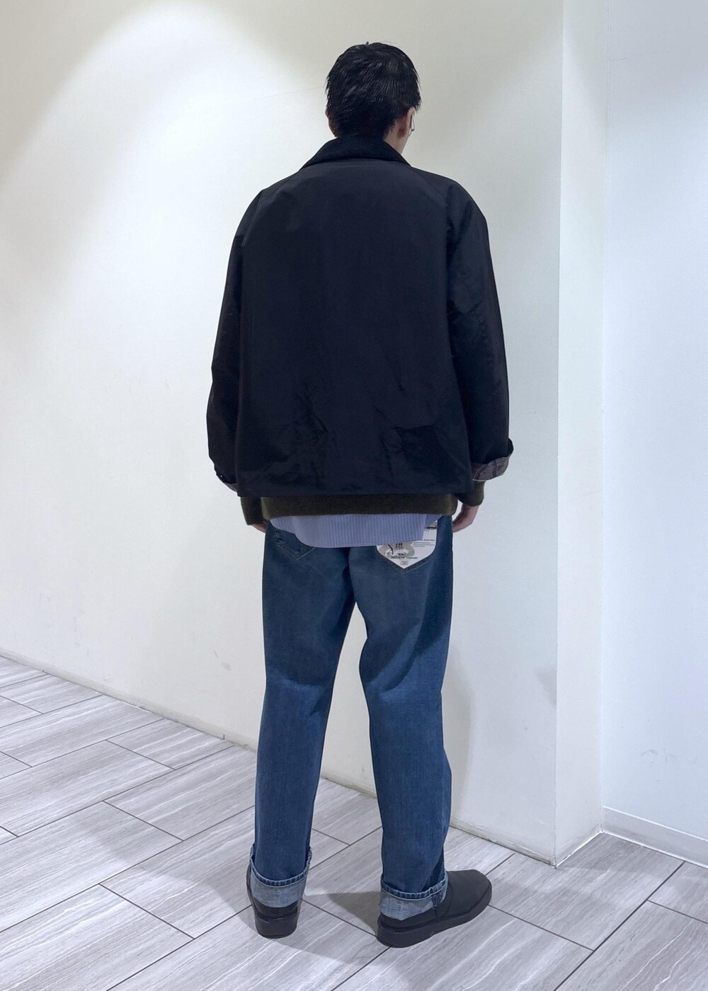ブルー系のデニムパンツ、ブラック系のブルゾン、グリーン系のカーディガン/ボレロを着用したメンズの秋コーディネートの4枚目の写真