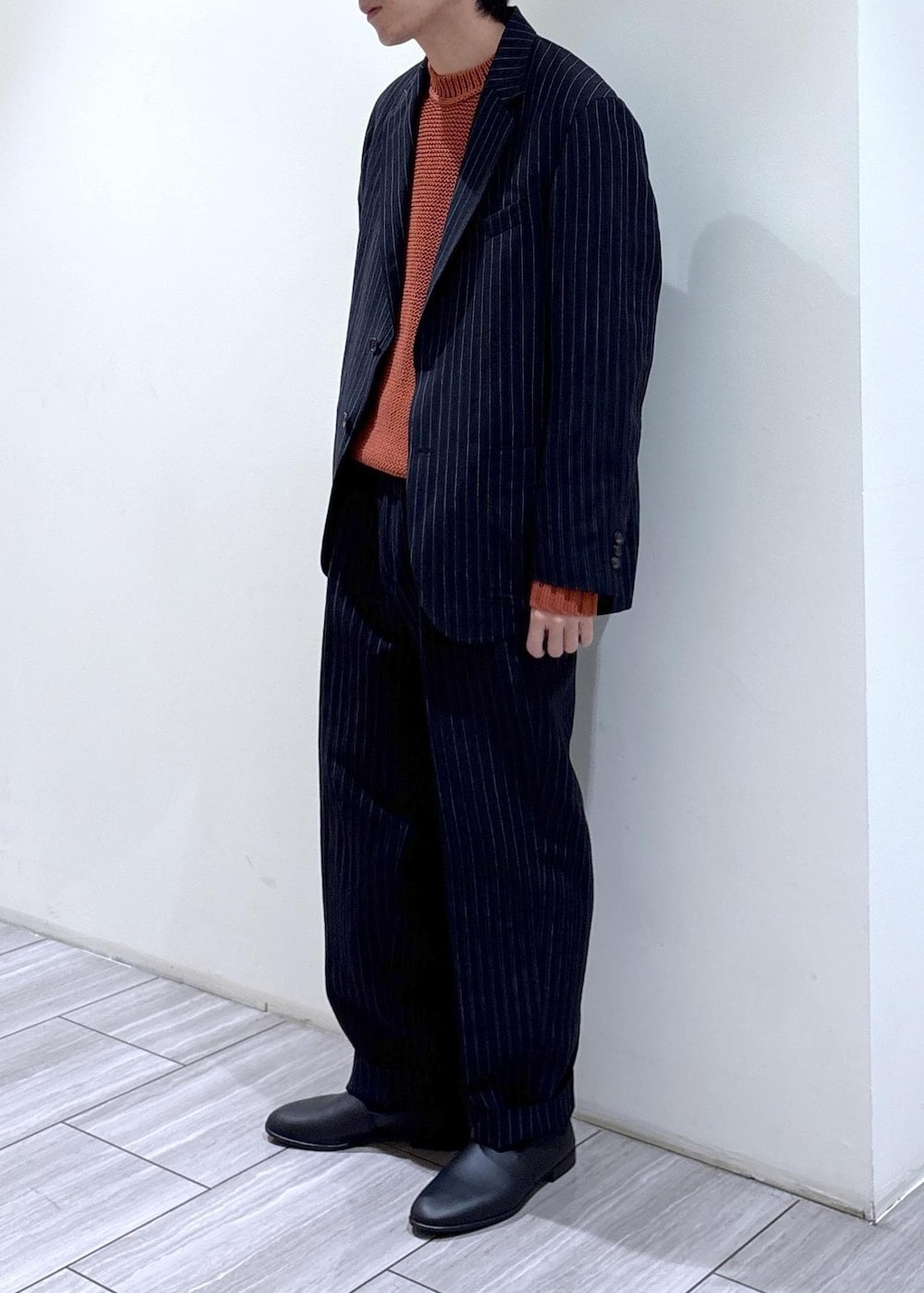 ブルー系のスラックス、ブルー系のノーカラージャケット、オレンジ系のニット/セーターを着用したメンズの冬コーディネートの3枚目の写真