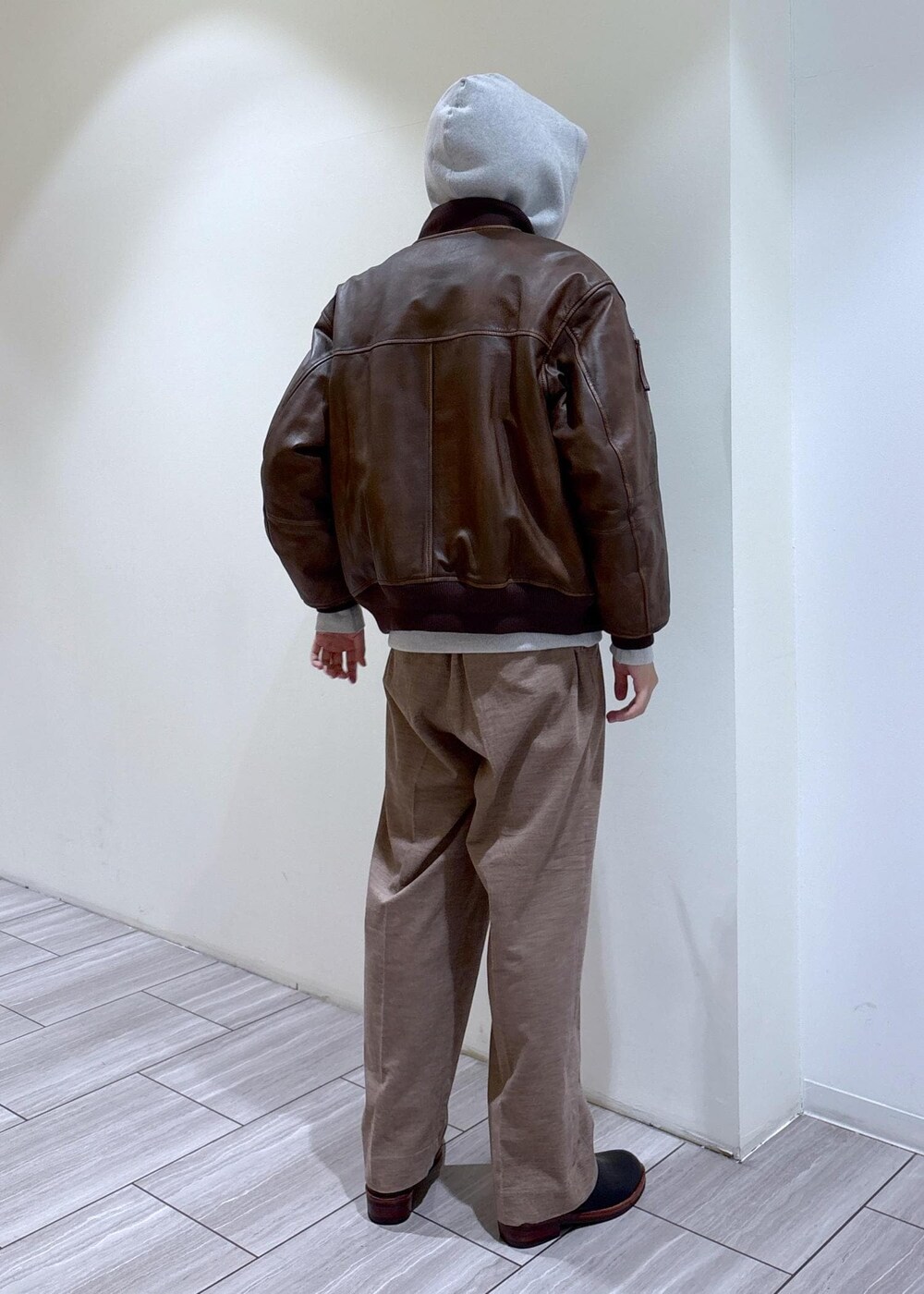 ブラック系のブーツ、グレー系のパーカー、ベージュ系のスラックスを着用したメンズの秋コーディネートの5枚目の写真