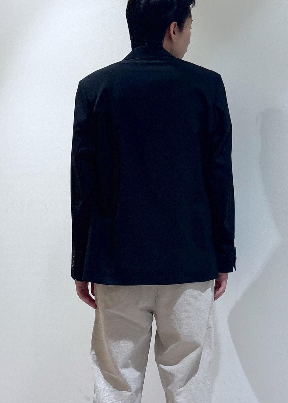 ブラック系のテーラードジャケット、ホワイト系のスラックス、ホワイト系のTシャツ/カットソーを着用したメンズの夏コーディネートの3枚目の写真