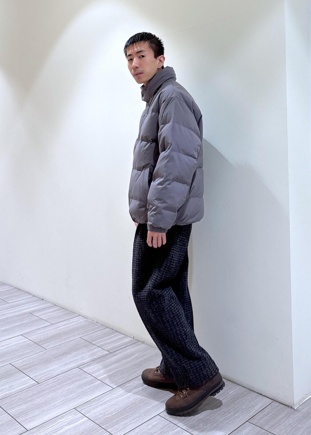 グレー系のダウンジャケット/コート、グレー系のスラックス、ブラウン系のブーツを着用したメンズの冬コーディネートの3枚目の写真