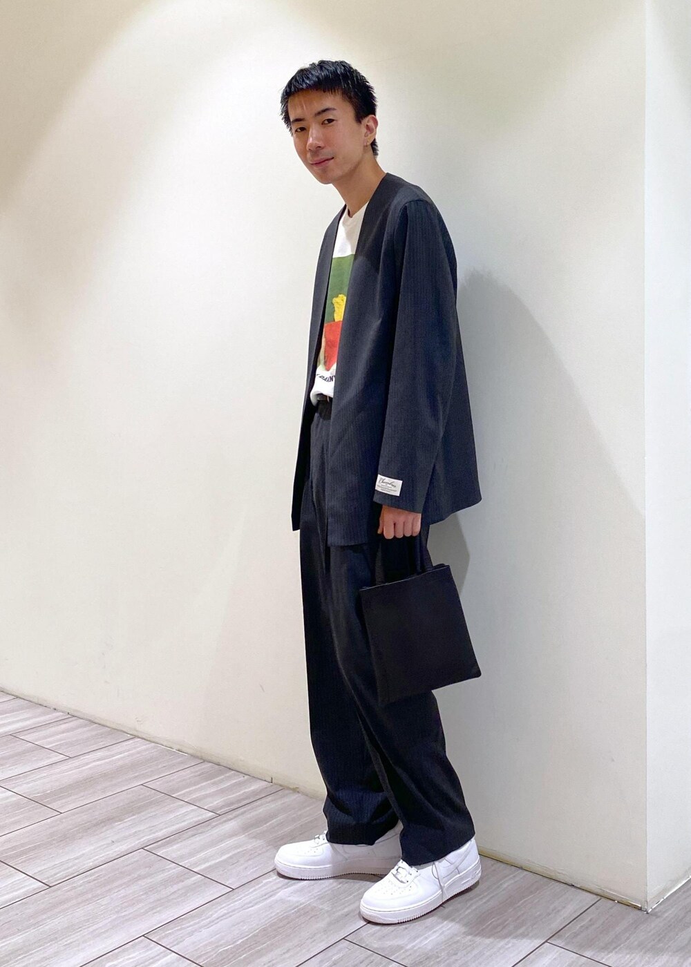 グレー系のノーカラージャケット、グレー系のスラックス、ホワイト系のスニーカーを着用したメンズの秋コーディネートの2枚目の写真