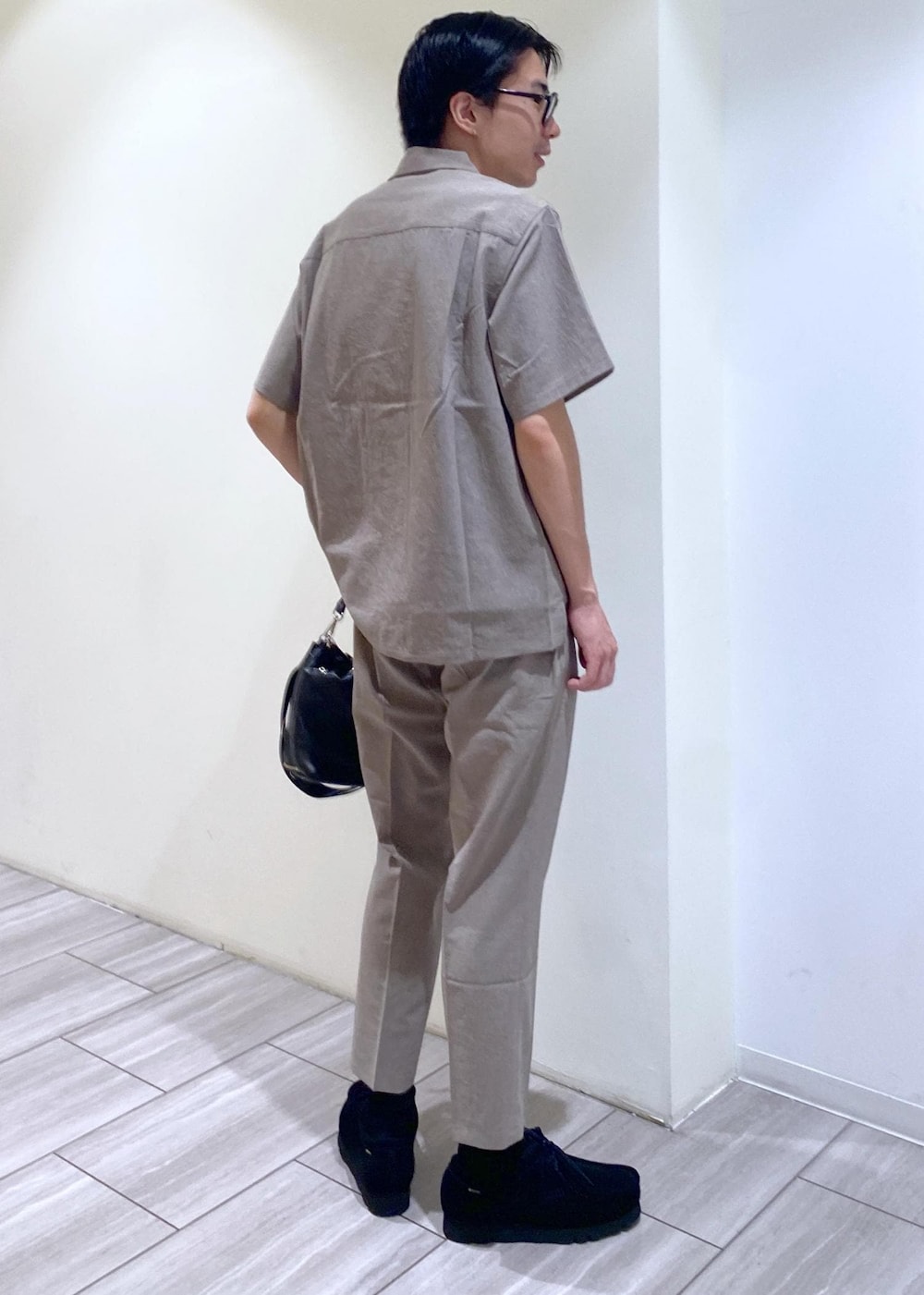 ベージュ系のセットアップ、ブラック系のTシャツ/カットソー、ブラック系のブーツを着用したメンズの夏コーディネートの4枚目の写真